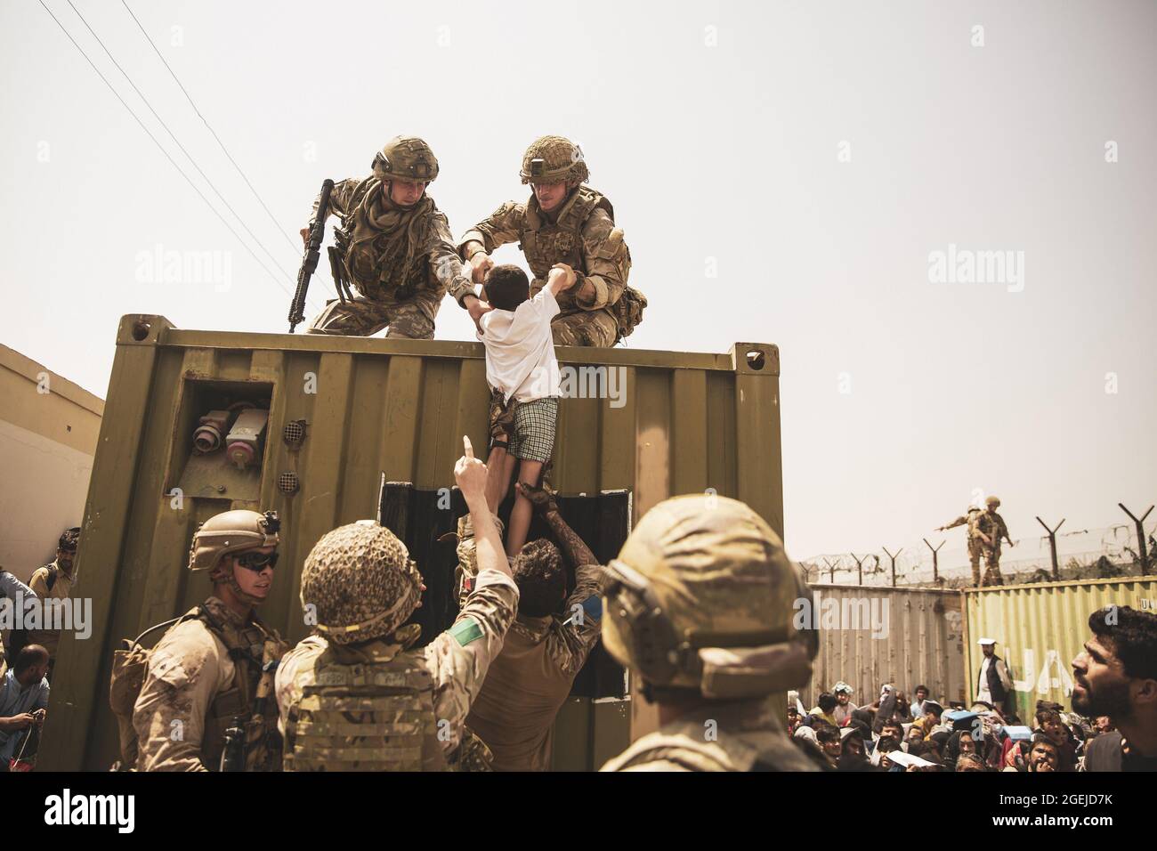 Kabul, Afghanistan. August 2021. Britische Koalitionstruppen, türkische Koalitionstruppen und US-Marineinfanteristen unterstützen ein Kind bei einer Evakuierung am Hamid Karzai International Airport in Kabul, Afghanistan, 20. August 2021. US-Dienstmitglieder unterstützen das Außenministerium bei einer nicht-kämpferischen Evakuierungsoperation (NEO) in Afghanistan. Foto von Staff Sgt. Victor Mancilla/USMC/UPI? Kredit: UPI/Alamy Live Nachrichten Stockfoto