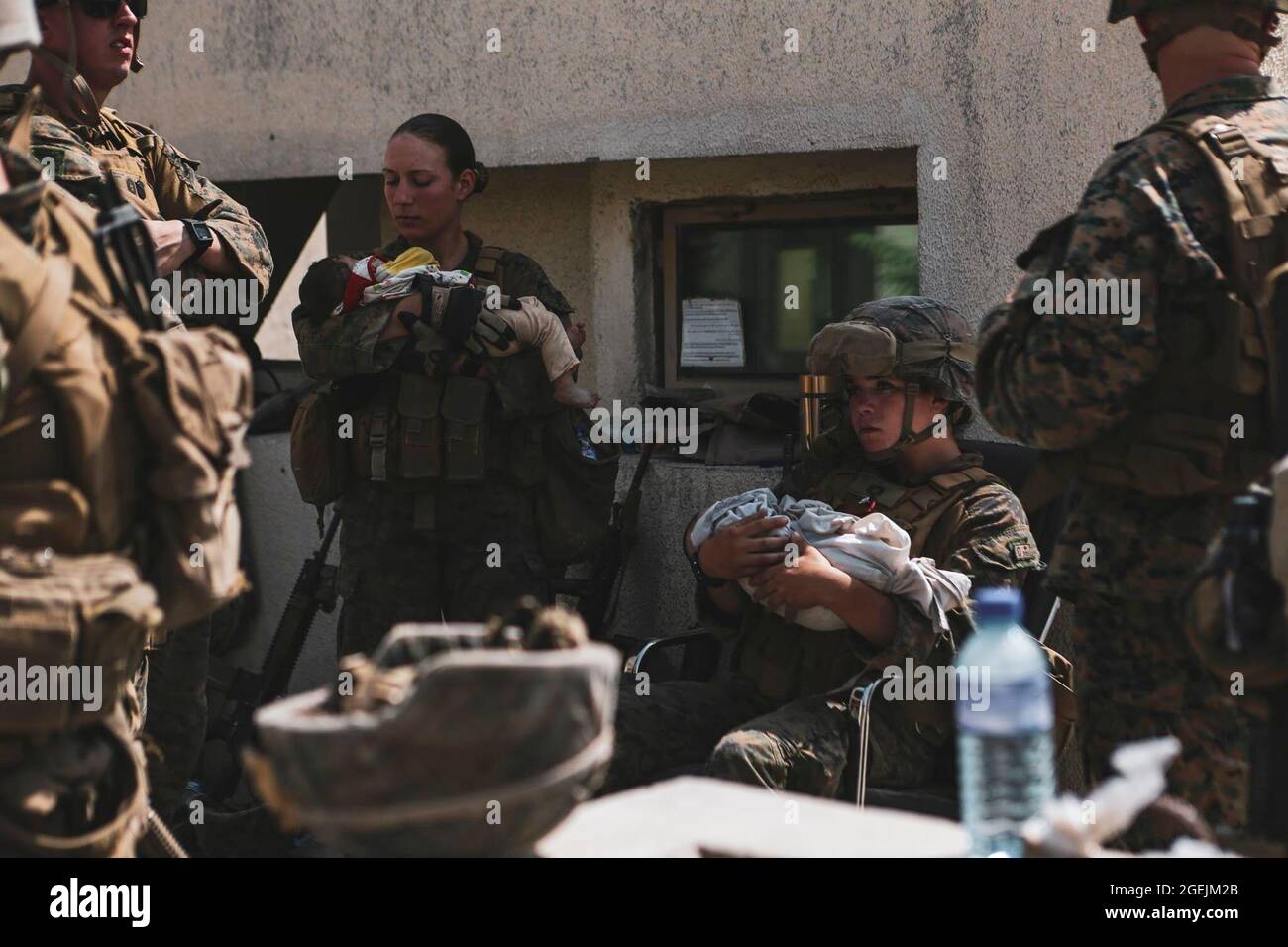 Schiffs-Sgt. Nicole Gee mit der 24. Marine Expeditionary Unit (MEU) (die später bei der IS-K-Bombenexplosion in Kabul getötet wurde), zweiter von links, zugewiesen an die 24. Marine Expeditionary Unit (MEU), beruhigen Säuglinge während einer Evakuierung am Hamid Karzai International Airport, Kabul, Afghanistan, August 20. US-Dienstmitglieder und Koalitionspartner unterstützen das Außenministerium bei einer nicht-kämpferischen Evakuierungsoperation (NEO) in Afghanistan. (USA Marine Corps Foto von Sgt. Isaiah Campbell) Gee war eines von 13 Dienstmitgliedern, die bei der Bombardierung getötet wurden. Stockfoto