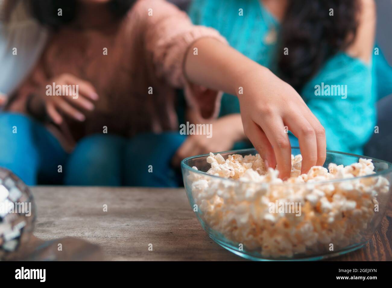 Nahaufnahme einer Hand, die Popcorn aus einer Schüssel nimmt, die Hand ist von einem Mädchen, das Gesicht wird nicht gesehen Stockfoto