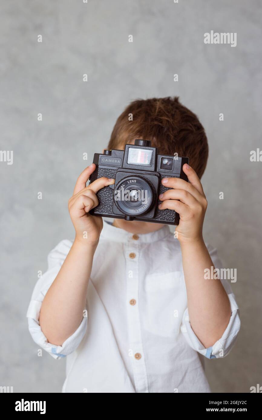 Kleiner Junge, der ein Foto mit analoger lomographie-Kamera im Vintage-Stil gemacht hat. Stockfoto