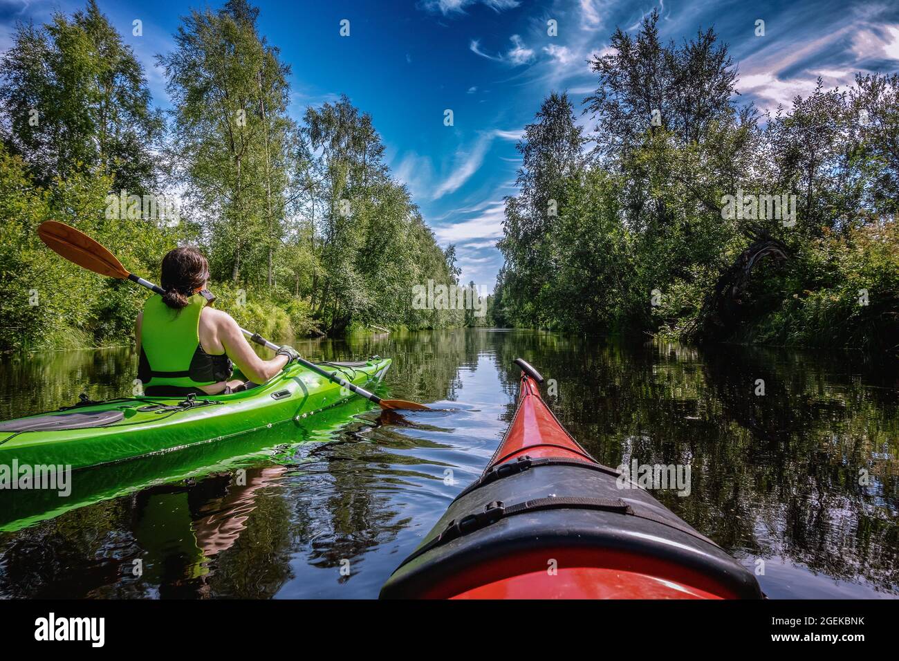 Mitteljährige kaukasische skandinavische Frauen Kajakfahren im kleinen Fluss Savaron im Wald, sonniger Sommertag, ausgezeichnete Sommeraktivitäten Nordschweden, Umea, Stockfoto