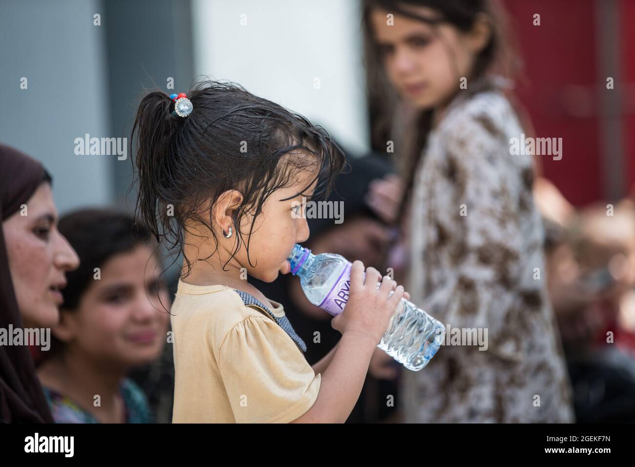 Kabul, Afghanistan. August 2021. Ein junges afghanisches Kind trinkt frisches Wasser, das während der Evakuierung von Zivilisten am Hamid Karzai International Airport im Rahmen der Operation Allies Refuge am 20. August 2021 in Kabul, Afghanistan, bereitgestellt wurde. Quelle: Planetpix/Alamy Live News Stockfoto