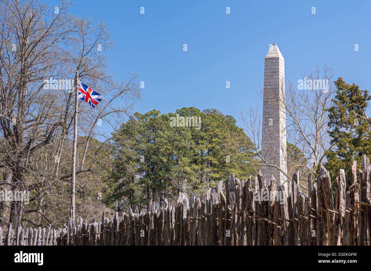 Jamestowne, VA, USA - 1. April 2013: Historische Stätte. Tencentennial Obelisk-Denkmal über Verteidigungsmauer von Fort gegen blauen Himmel gesehen. Etwas grünes Laub Stockfoto