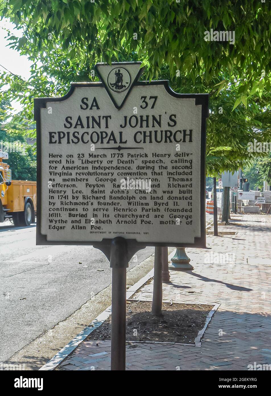 Richmond, VA, USA - 19. Juni 2006: Schild, das die Geschichte der historischen Kirche Saint Johns erzählt, sagt es in Schwarz auf Weiß entlang der Straße unter grünem Laub. Stockfoto