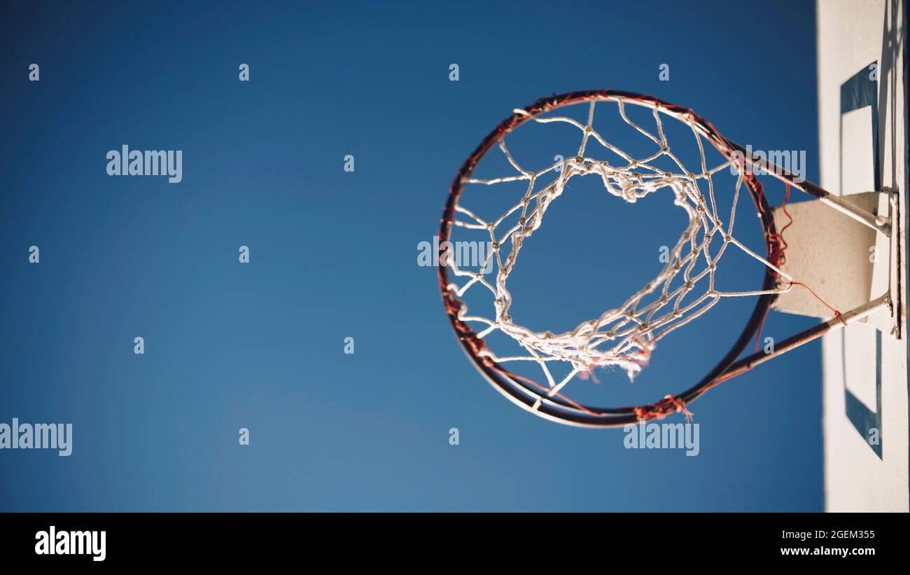 Basketballkorb mit Netz im Flugzeug von unten mit blauem Himmel Stockfoto