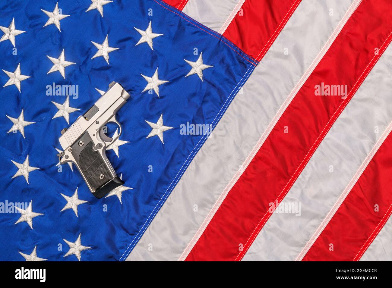 Auf einer amerikanischen Flagge steht eine Chrompistole, die die Freiheit und das Recht des zweiten Amendments symbolisiert, Waffen zu tragen. Stockfoto
