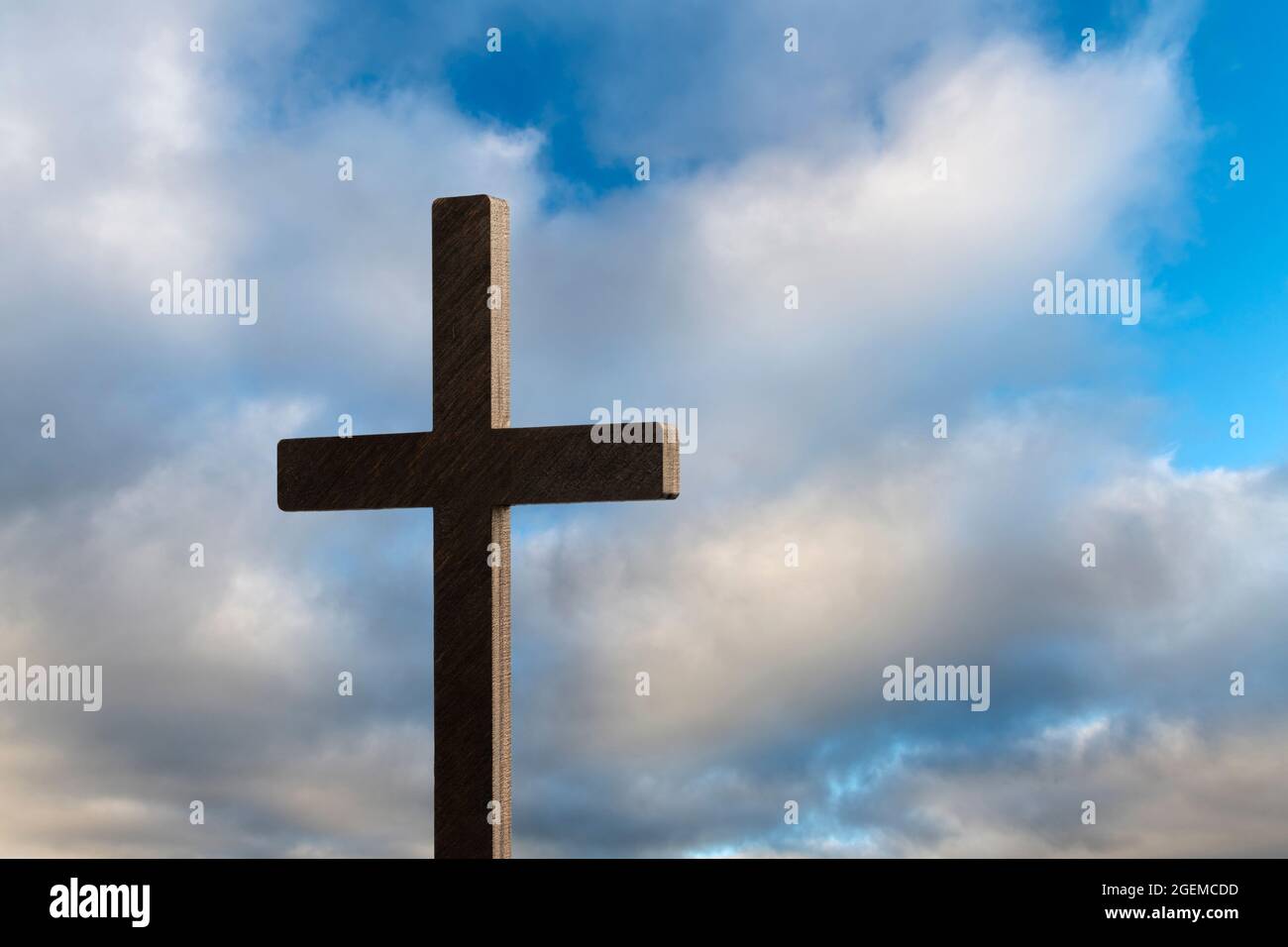 Dramatisches Bild mit einem religiösen Kirchenkreuz, eingerahmt von einem blauen, wolkigen Himmel. Platz auf der rechten Seite des Kreuzes kopieren. Stockfoto