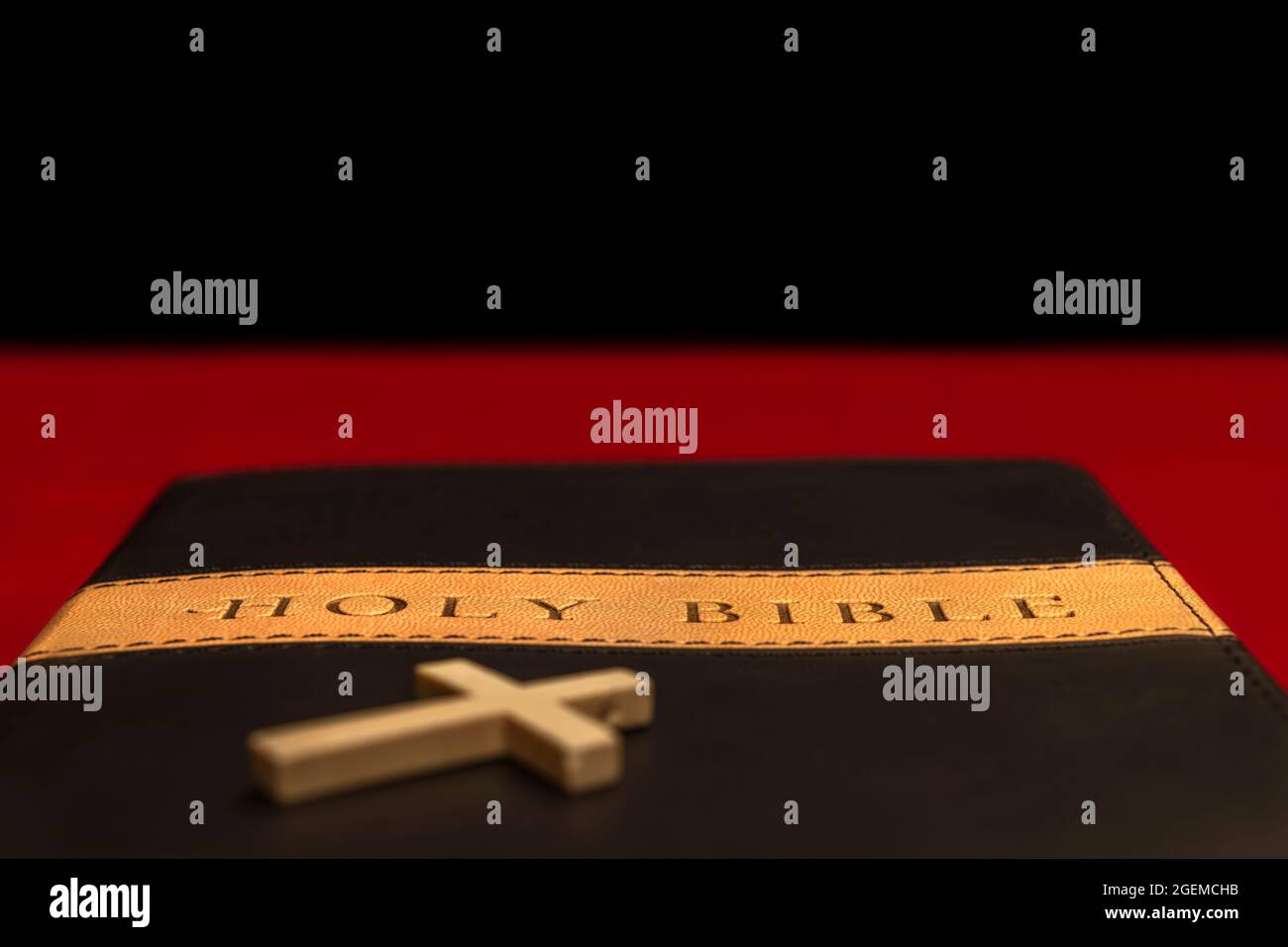 Heilige bibel auf rotem Tisch mit einem kleinen Kruzifix im Vordergrund, mit selektivem Fokus auf den Titel des Buches. Stockfoto Heilige bibel auf rotem Tisch mit einem kleinen Kruzifix im Vordergrund, mit selektivem Fokus auf den Titel des Buches. Stockfoto