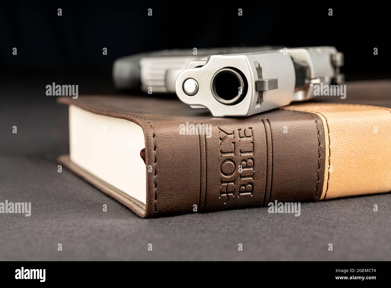 Eine Waffe ruht auf einer heiligen bibel, die Gott, Waffen und Religionsfreiheit repräsentiert. Stockfoto