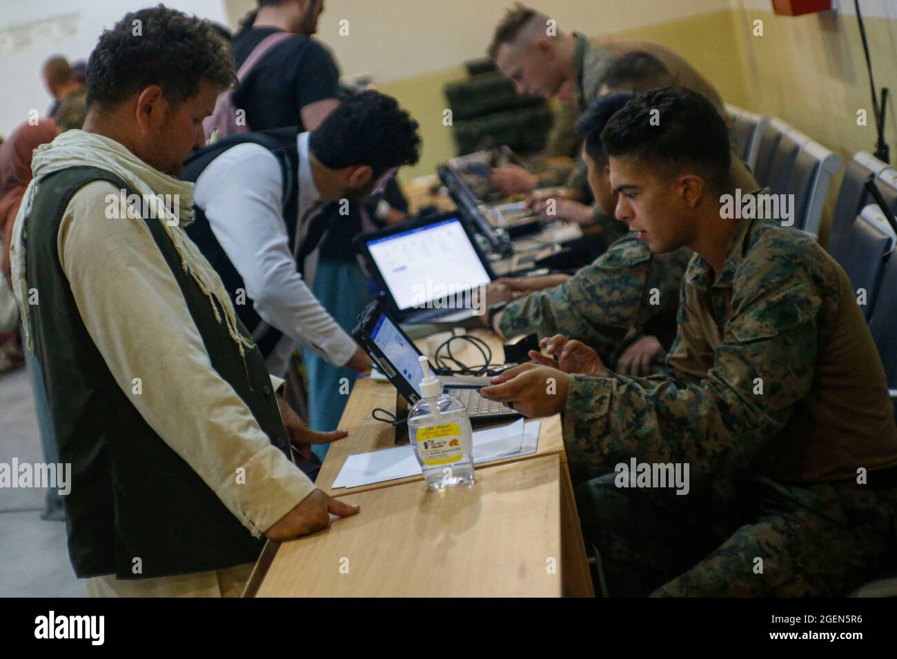 Eine US-Marine, die der 24. Marine Expeditionary Unit zugewiesen ist, überprüft vor ihrem Flug evakuierte Personen während einer Evakuierung am Hamid Karzai International Airport, Afghanistan, 18. August 2021. US-Dienstmitglieder unterstützen das US-Außenministerium bei einer geordneten Abseichung von designiertem Personal in Afghanistan. Obligatorische Gutschrift: Nichola Guevara/US Marine Corps über CNP Stockfoto