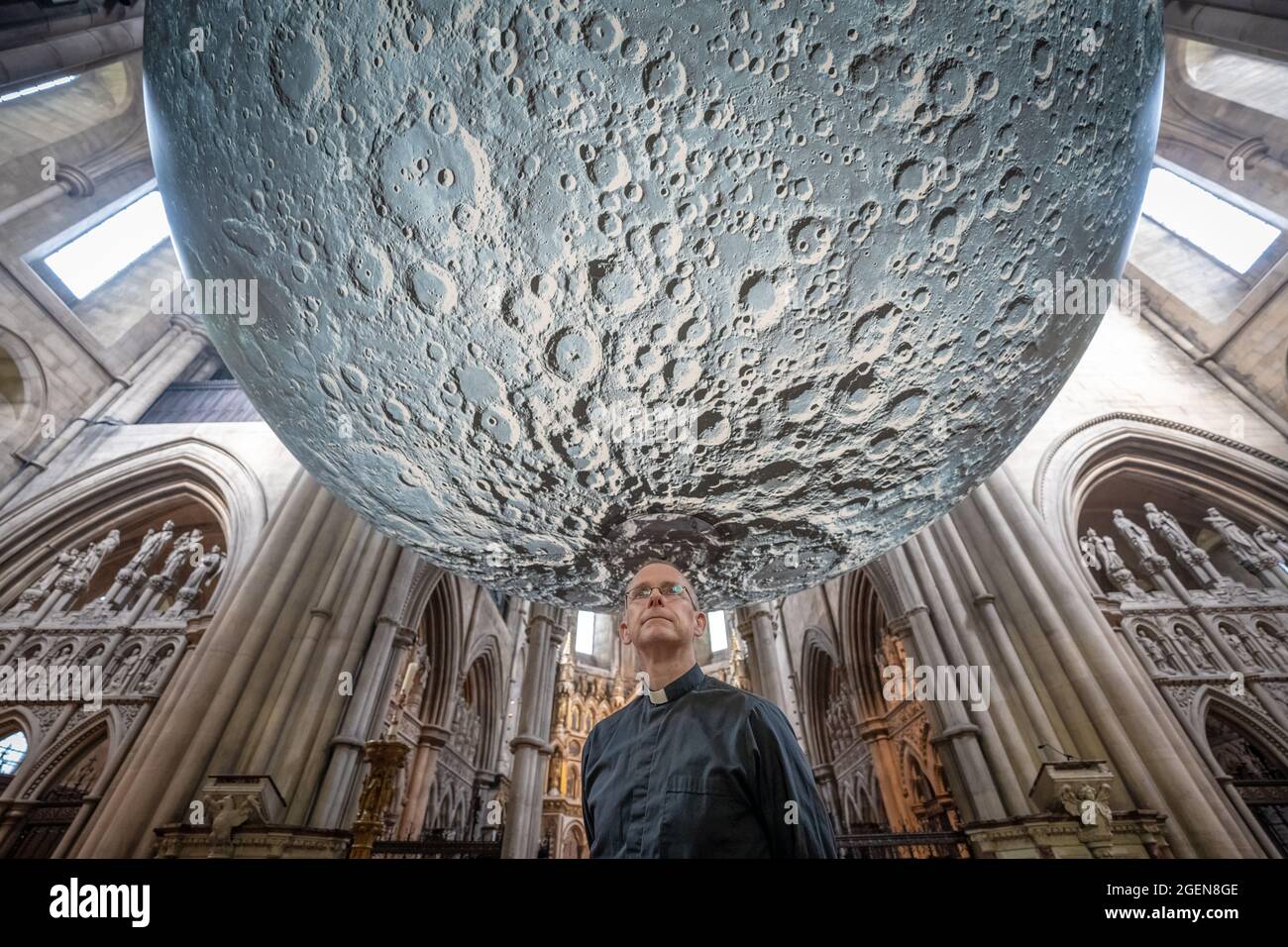 Der Resident Vicar, James Heard, steht mit der Installation des Museum of the Moon des Künstlers Luke Jerram in der St. John the Baptist Kirche im Westen Londons, Großbritannien. Stockfoto