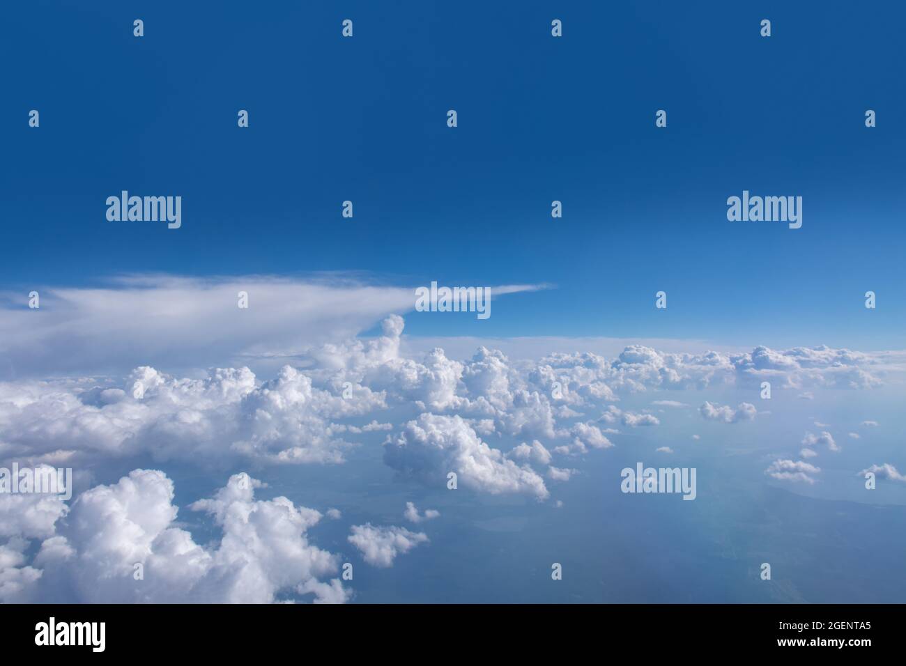 Schöne Cumulus flauschige weiße Wolken auf einem blauen Himmel mit heller Sonne. Perfekte abstrakte Himmel Hintergrund, Tapete, Layout. Sonnenaufgang über Wolken aus der Luft Stockfoto