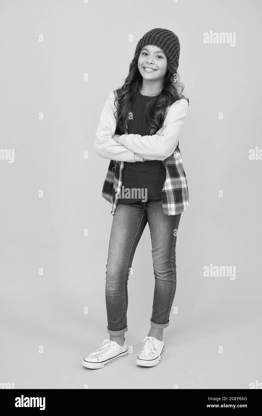 Fröhliches Kind trägt legere Denim-Kleidung und hat lange lockige Haare, Stil Stockfoto