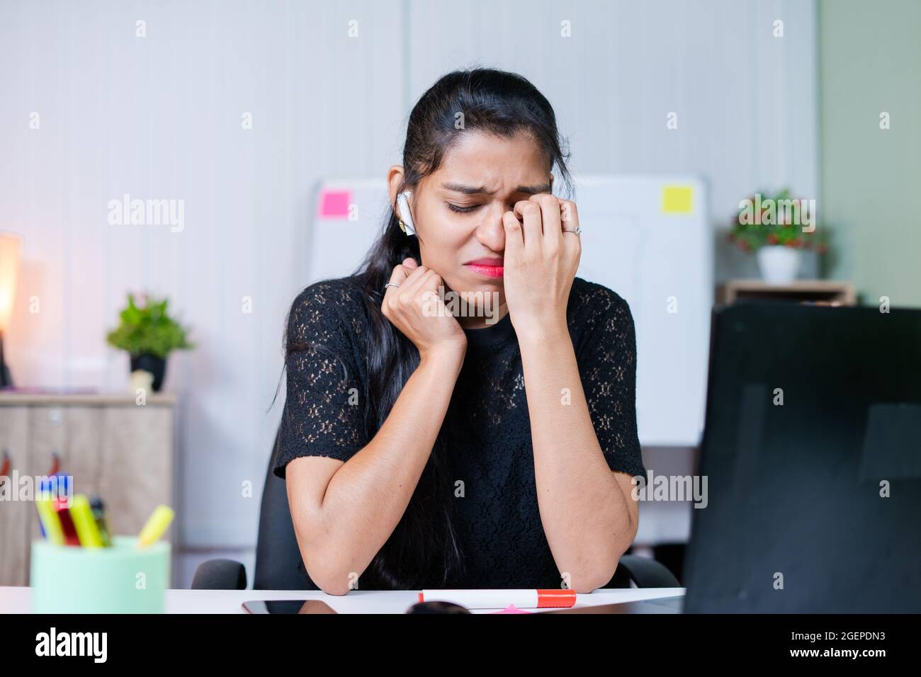 Mittlere Aufnahme einer frustrierten, traurig weinenden jungen inderin am Arbeitsplatz - Konzept von emotionalem, mentalem oder Arbeitsstress im Büro. Stockfoto