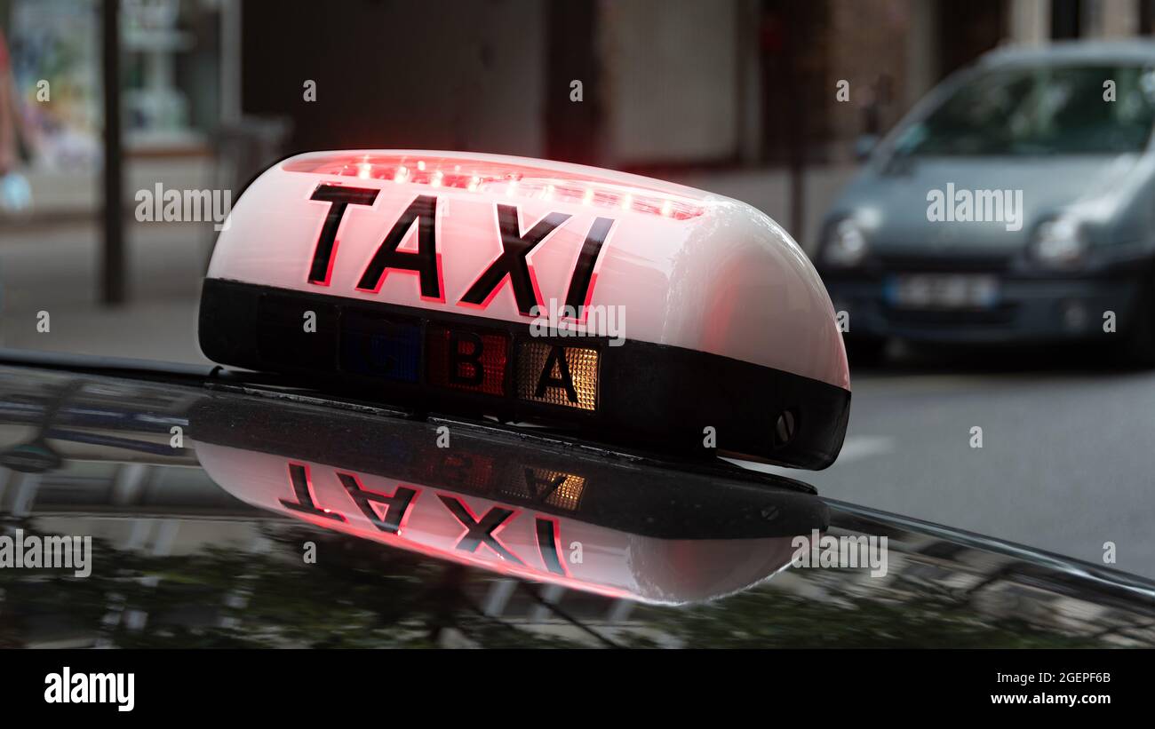 Beleuchtetes Dachschild mit dem Wort TAXI, das an einem Fahrzeug in einer Straße von Paris, Frankreich, angebracht ist Stockfoto