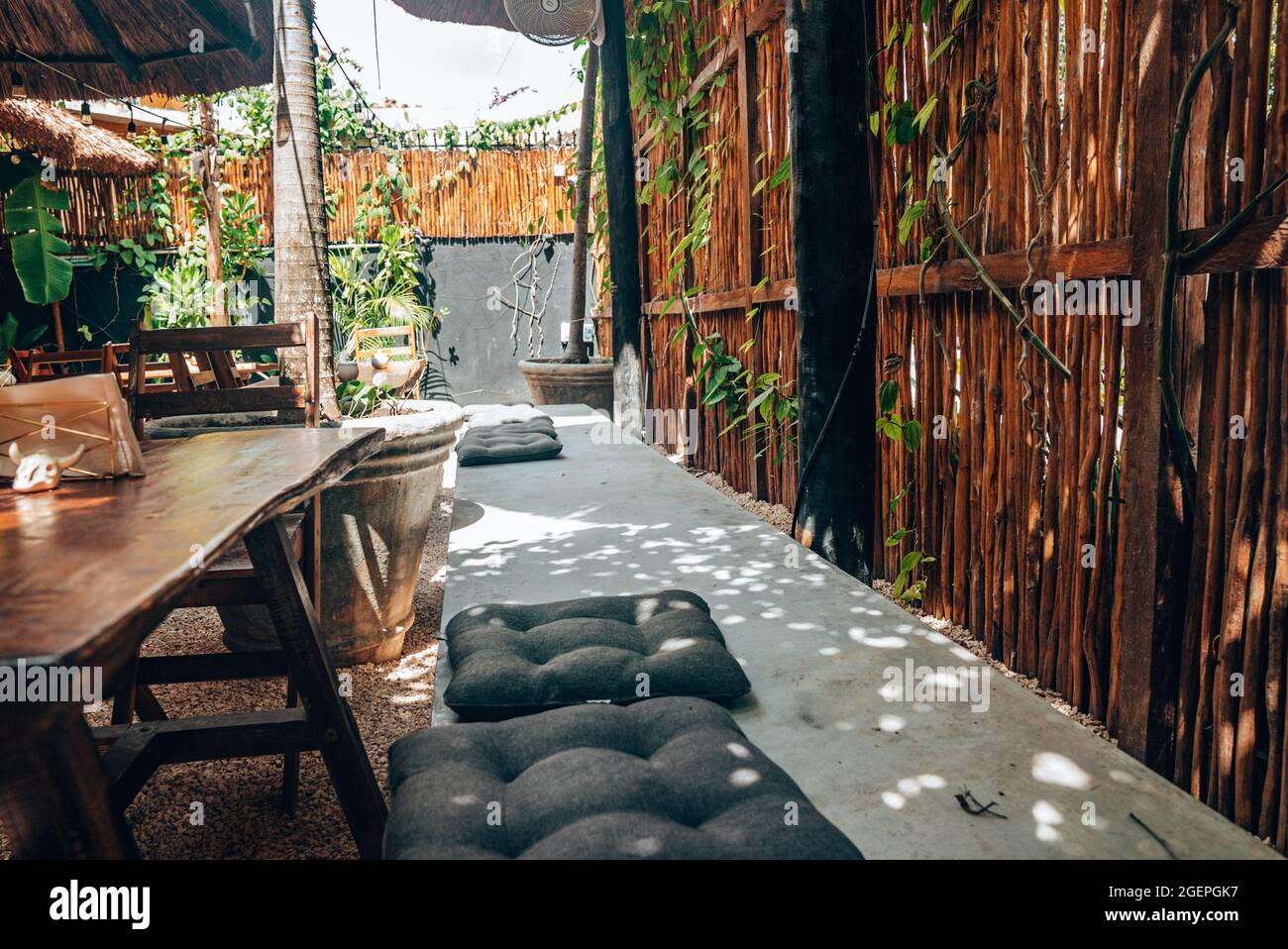 Leere Holzstühle und -Tische mit Kissen auf Betonbank im Café im Freien Stockfoto