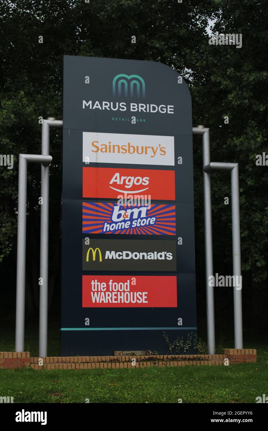 Schild mit Werbung für Sainsburys, Argos, B&M, McDonalds und das Lebensmittellager. Marus Bridge Retail Park, Wigan Stockfoto