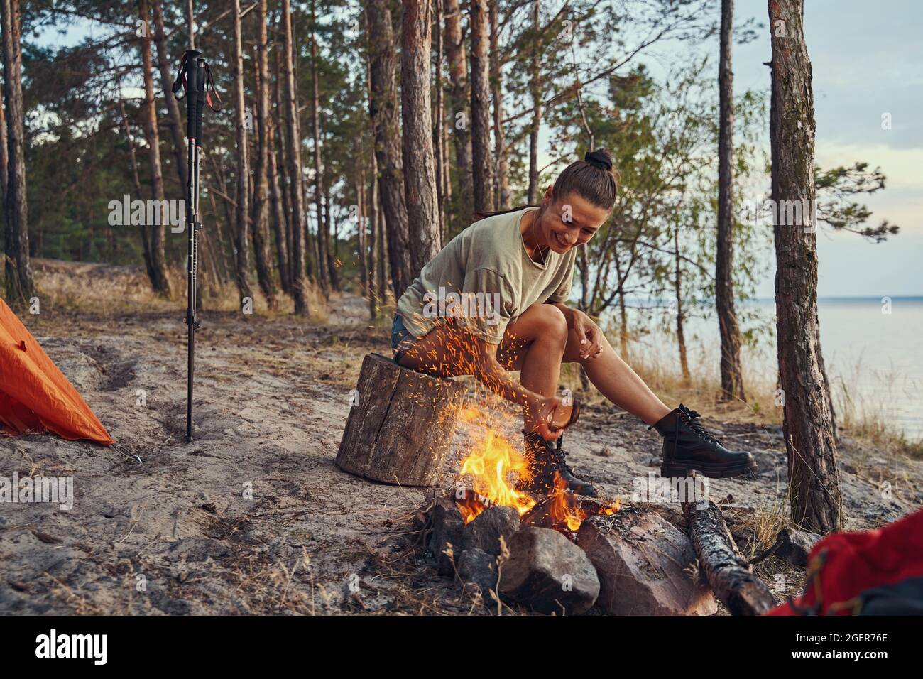 Tourist in ihrem Lager, der Log in Lagerfeuer setzte Stockfoto Tourist in ihrem Lager, der Log in Lagerfeuer setzte Stockfoto