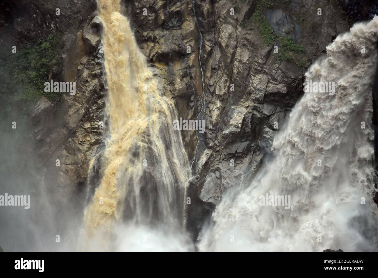 Ein matschiger brauner Wasserfall und ein klarer weißer Wasserfall, fotografiert mit hoher Geschwindigkeit in Baños de Agua Santa - Ecuador Stockfoto