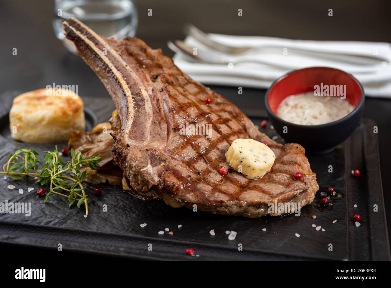 Gegrilltes Kalbsschnitzel auf schwarzem Steinteller mit Sauce und Garnitur. Stockfoto