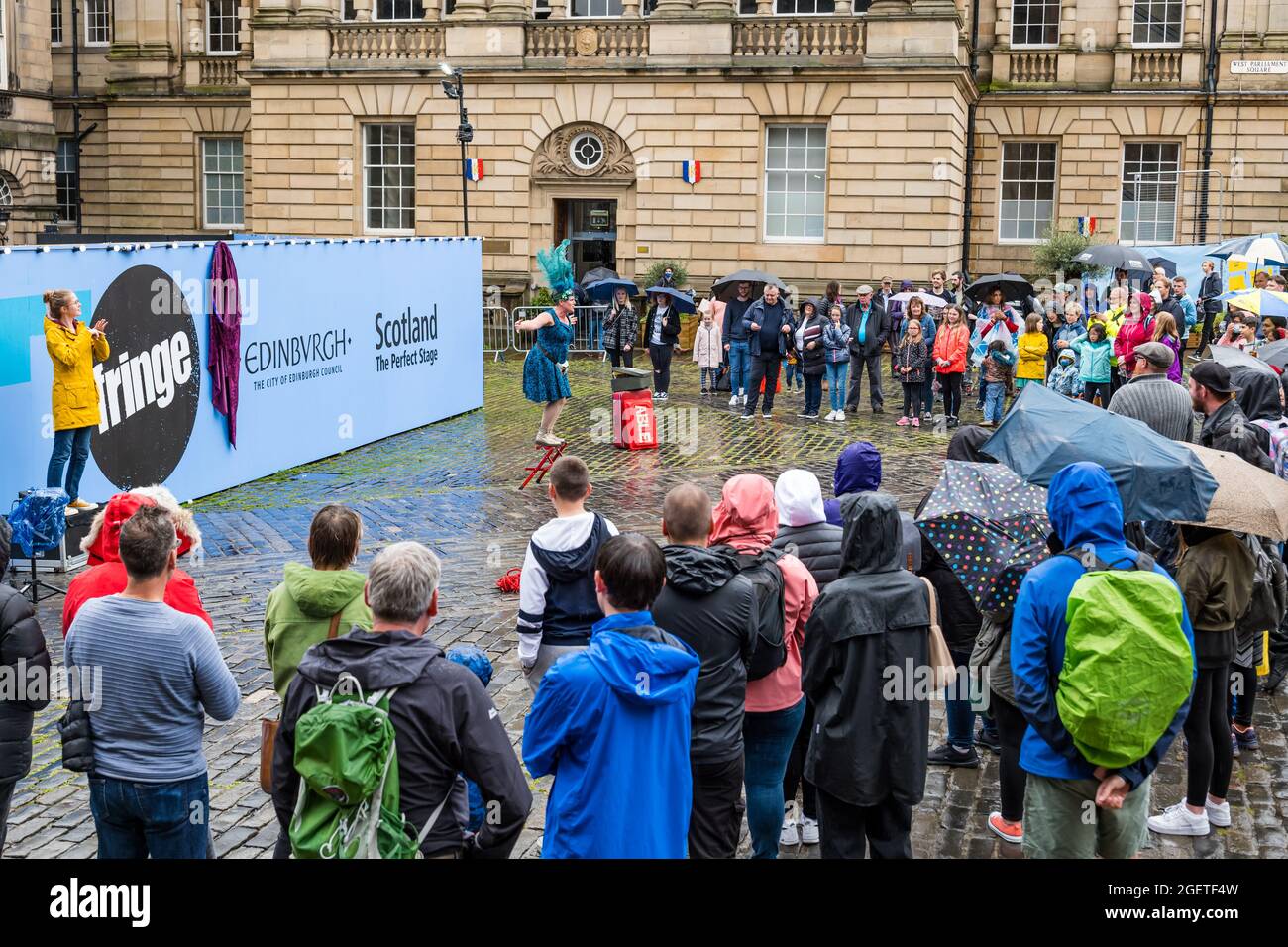 Royal Mile, Edinburgh, Schottland, Großbritannien, 21. August 2021. UK Wetter: Regen am Edinburgh Festival Fringe. Das trostlos nasse Wetter schreckt die Fringe-Massen oder die Straßenkünstler auf einem zurückgeschreckt Festival in diesem Sommer nicht ab. Eine Darstellerin auf dem Parliament Square mit einer Frau, die in Gebärdensprache dolmetscht Stockfoto