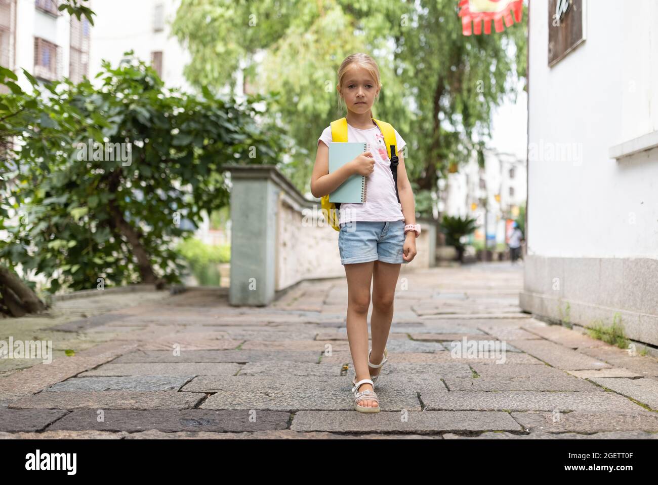 Schulmädchen zurück zur Schule nach den Sommerferien. Happy Child lächelt am frühen Morgen draußen. Stockfoto