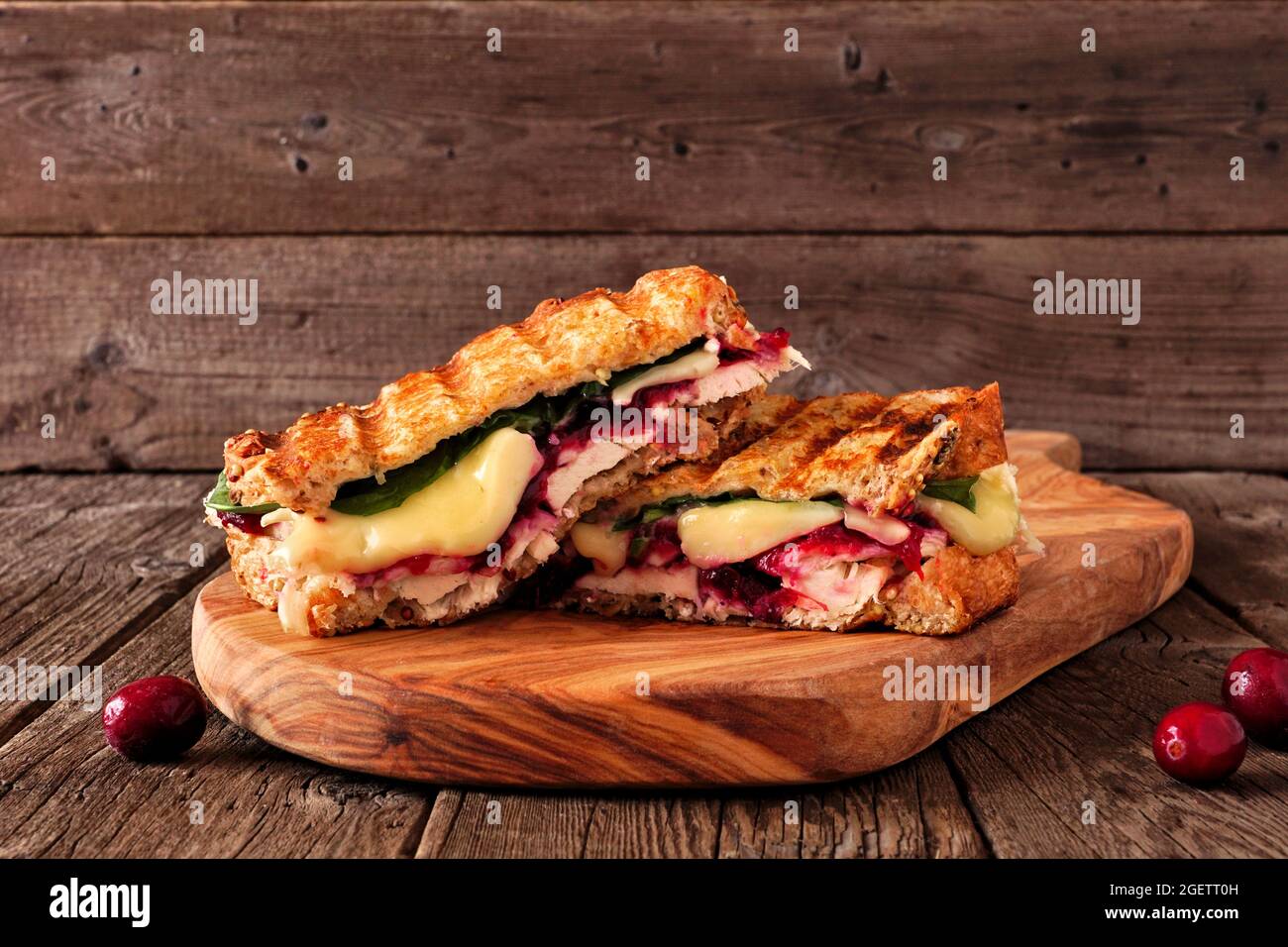 Gegrillter truthahn, Cranberry- und Brie-Sandwich. Seitenansicht auf einem Servierbrett vor dunklem Holzhintergrund. Stockfoto