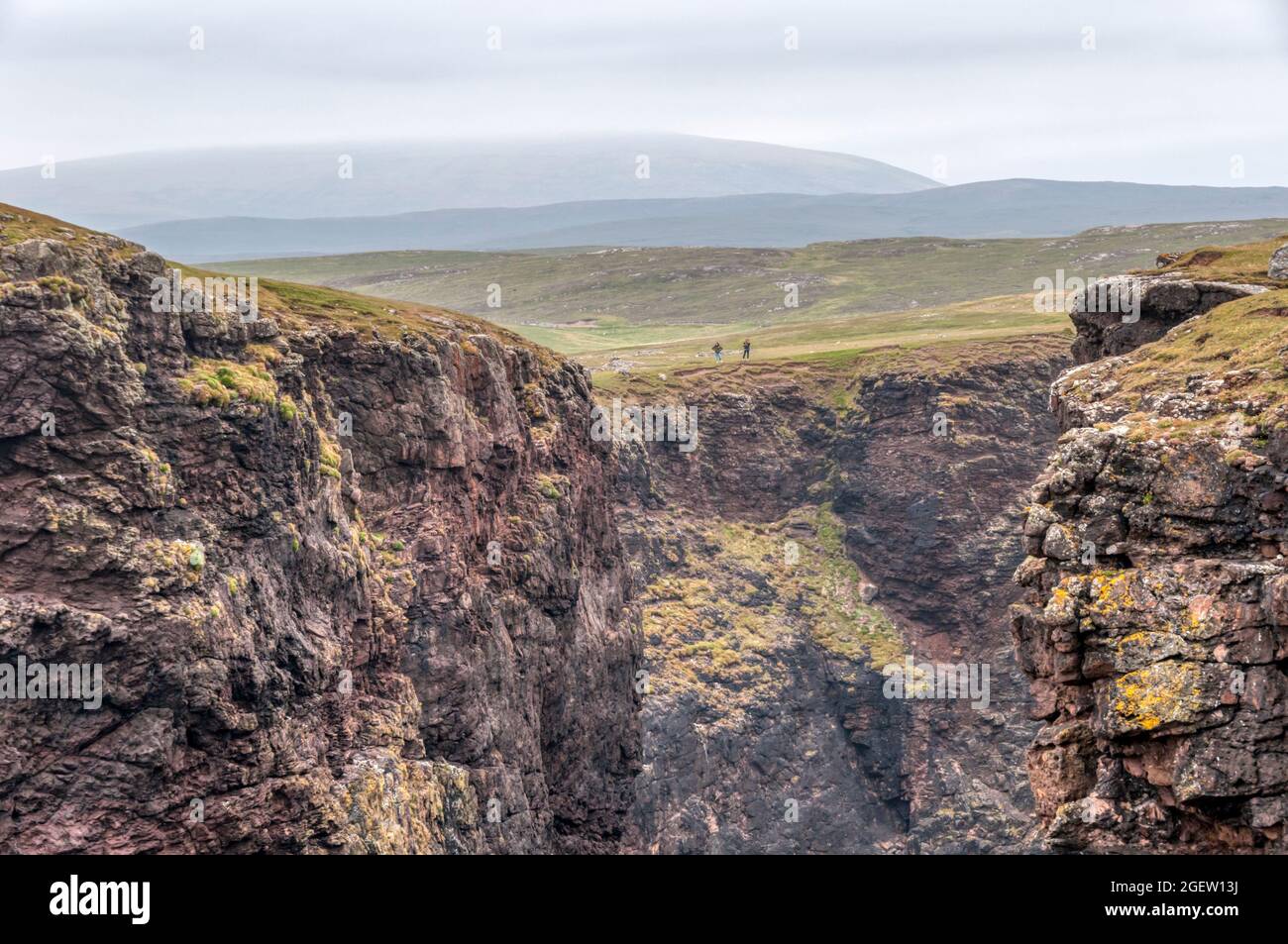 Ein Paar Wanderer bewundern die Aussicht auf Eshaness oder Esha Ness in Northmavine auf dem Festland Shetland. Stockfoto