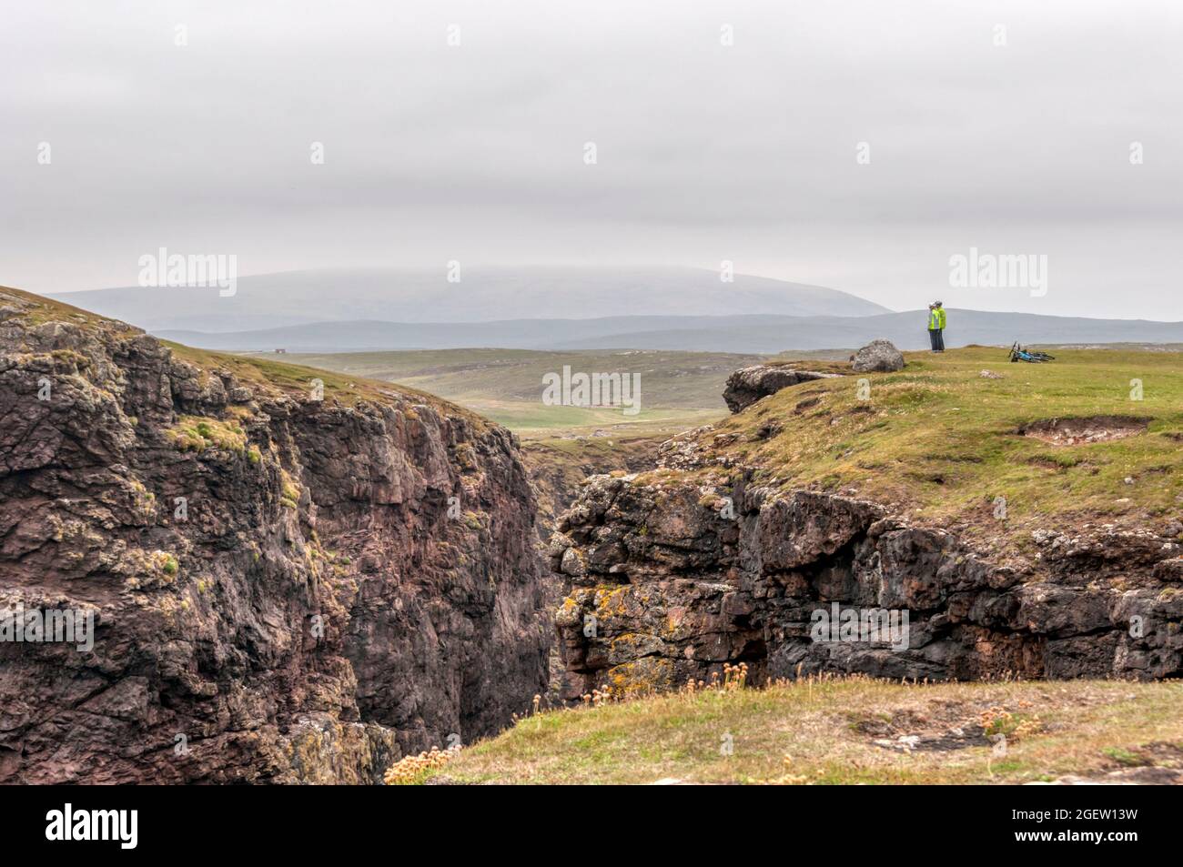 Ein Paar Radfahrer hält an, um die Aussicht auf Eshaness oder Esha Ness in Northmavine auf dem Festland Shetland zu bewundern. Stockfoto