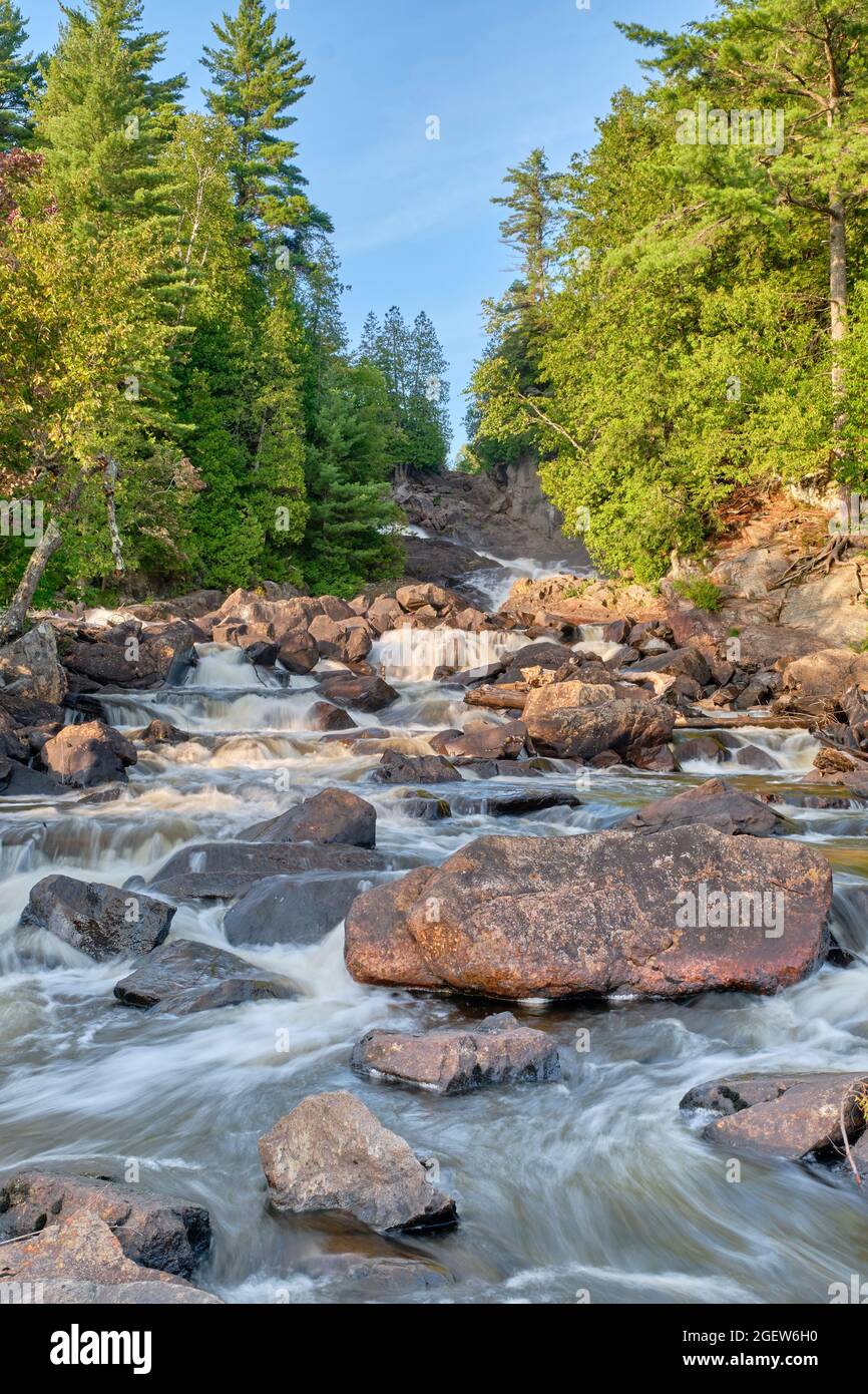 Ein Sonnenuntergangsfoto vom Grund der Ragged Falls am Oxtongue River, direkt vor dem Algonquin Park, mit dem Wasser, das über die Granitfelsen donnert Stockfoto