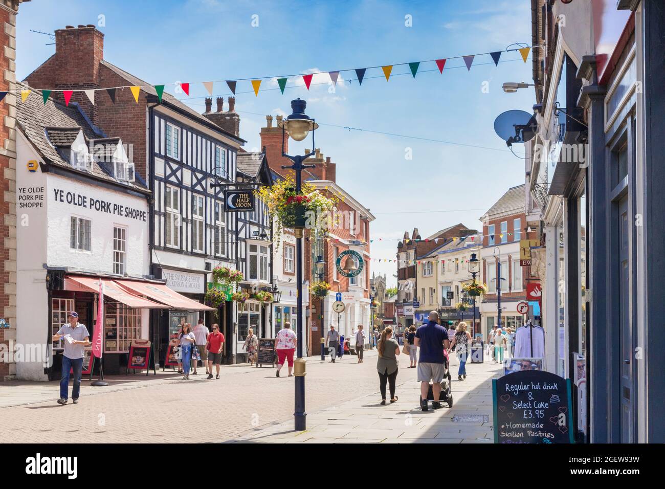 4. Juli 2019: Melton Mowbray, Leicestershire, Großbritannien - Menschen, die an einem warmen Sommertag in der Nottingham Street einkaufen. Ye Olde Pork Pie Shoppe auf der linken Seite. Stockfoto