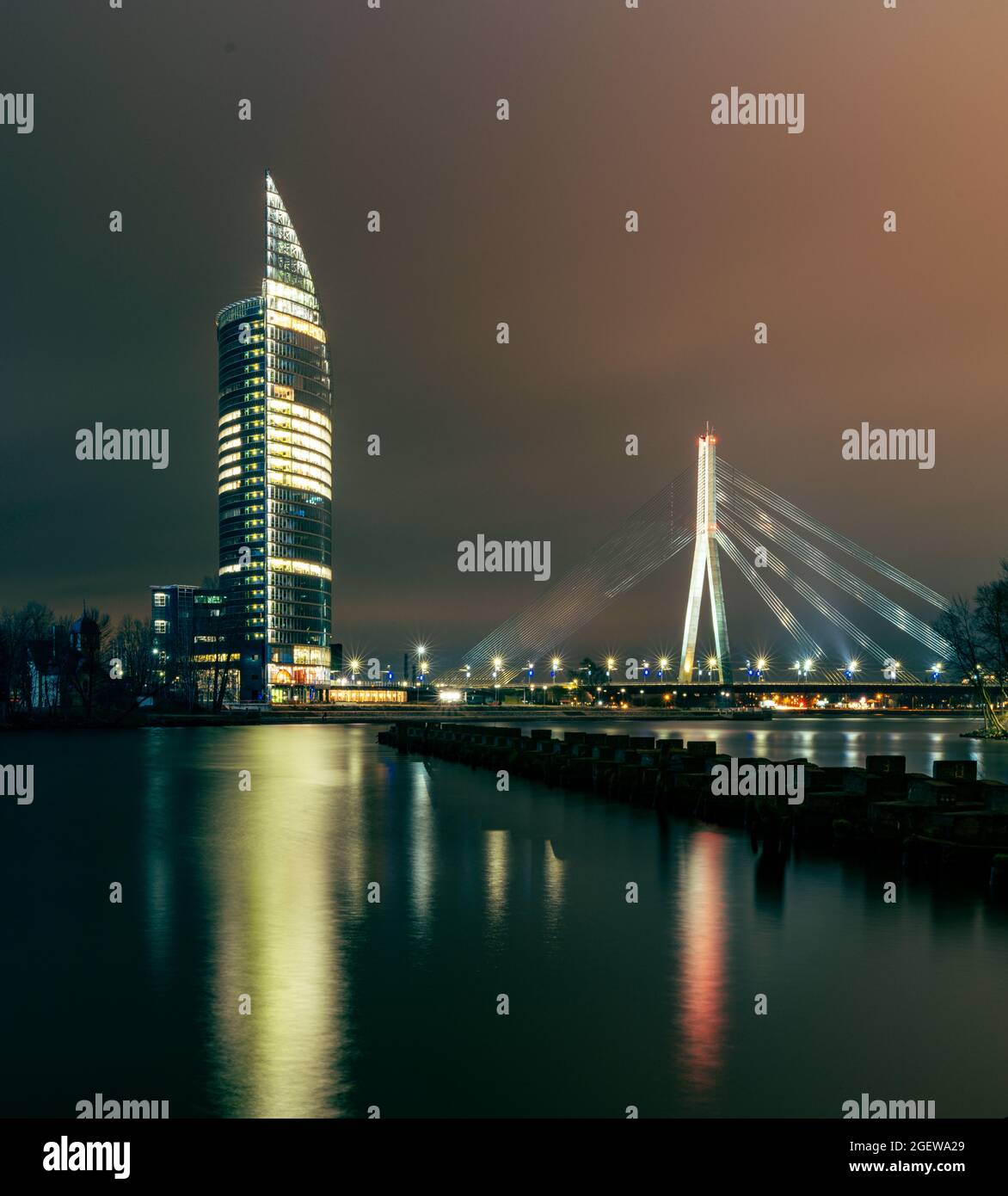 Nachtansicht über den Wasserkörper, den Fluss zur Brücke und das Hochhaus und die Lichter der Stadt, die das Wasser reflektieren. Blick von der Bucht von Agenskalns auf die CI Stockfoto