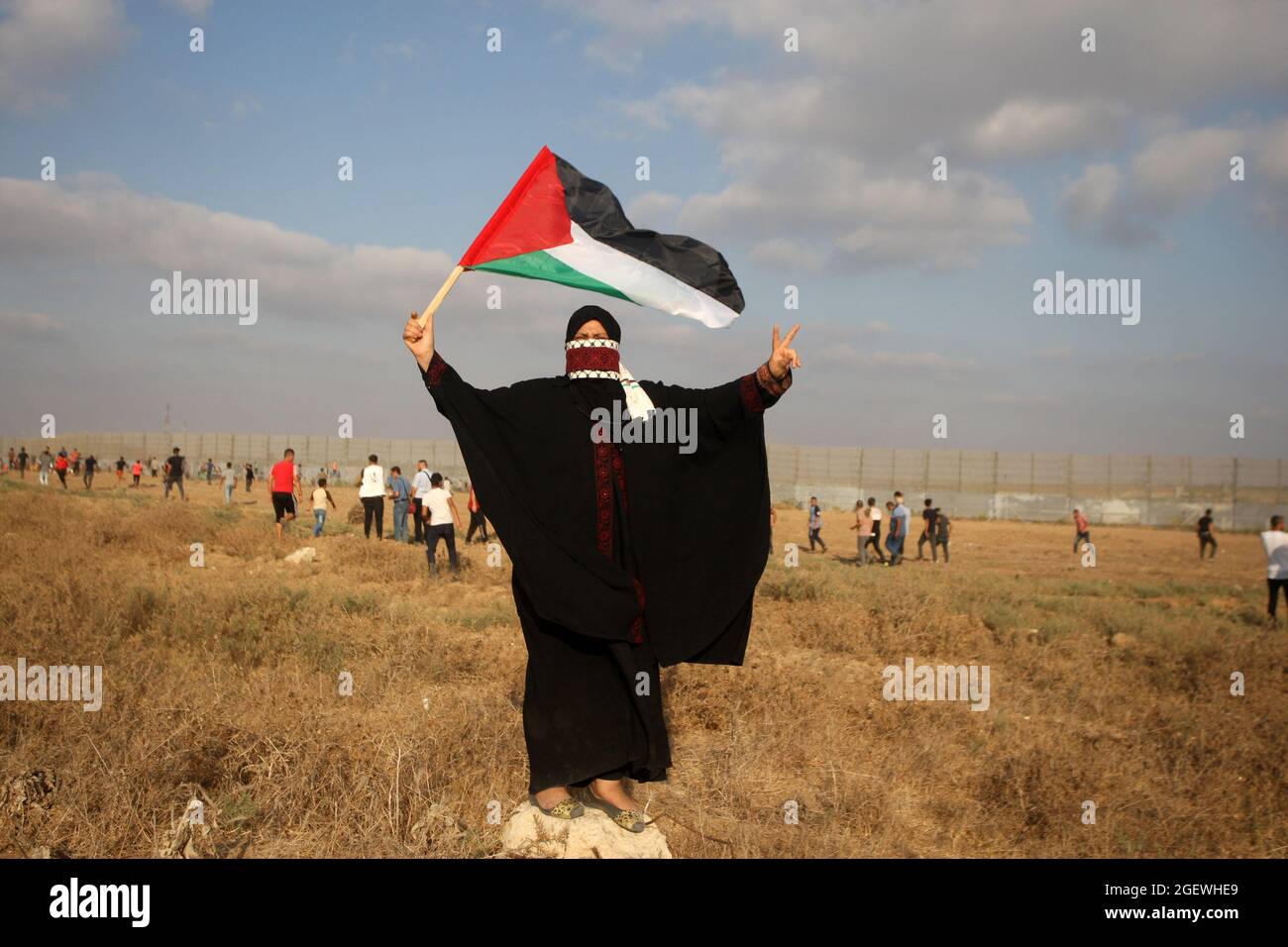 Gaza, Gaza. August 2021. Eine palästinensische Protesterin hebt die Nationalflagge auf, als sie an einer Demonstration am Grenzzaun mit Israel östlich von Gaza-Stadt teilnimmt und die israelische Belagerung des palästinensischen Streifens am samstag, den 21. August 2021, am samstag, den 21. August 2021 anprangert. Foto von Ismael Mohamad/ Quelle: UPI/Alamy Live News Stockfoto