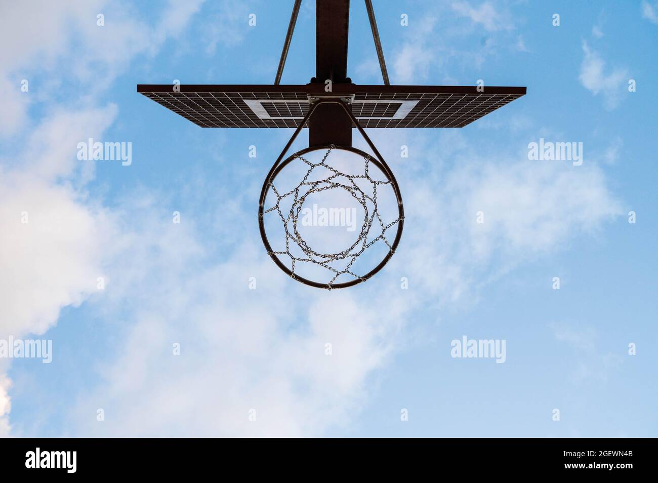Ansicht von unten auf einen metallischen Street-Basketball-Reifen im Freien mit einem blauen Himmel im Hintergrund. Stockfoto