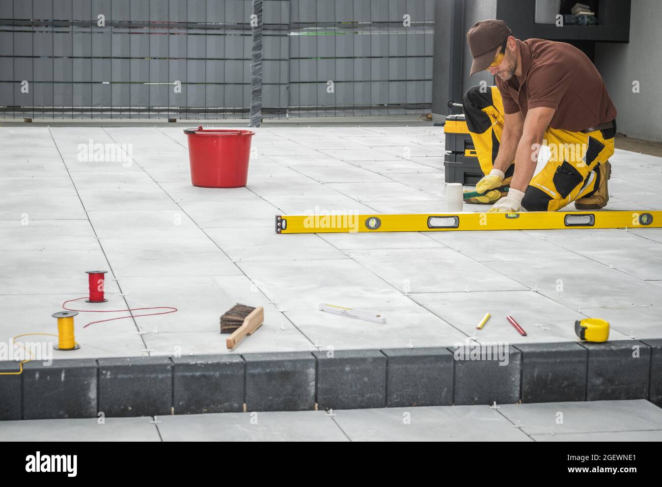 Outdoor Patio Fliesen Installation von professionellen kaukasischen Arbeiter in seinen 40er Jahren. Männer Finishing Patio Boden Mit Flexiblen Hammer. Stockfoto