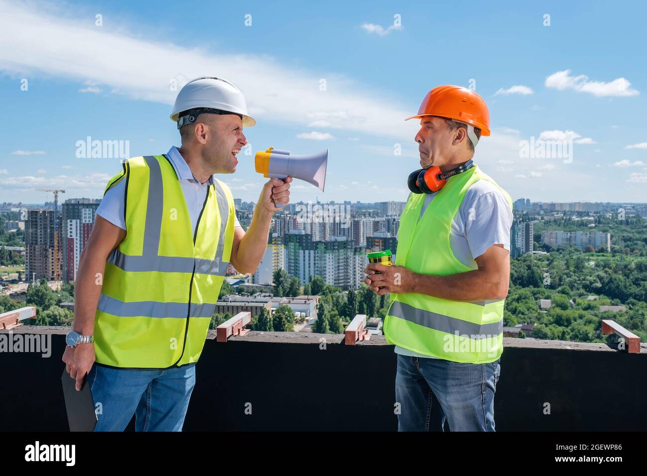 Wütender Chef brüllt im Megaphon vor seinem Baumeister auf der Baustelle Stockfoto