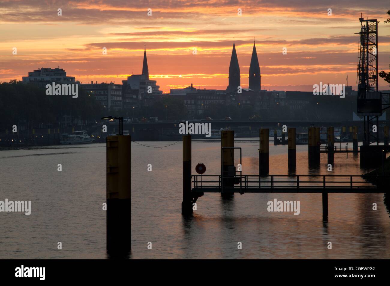 Schöner Sonnenaufgang mit dramatischem Himmel an der Weser in Bremen, Deutschland mit Kirchtürmen im Stadtbild Stockfoto