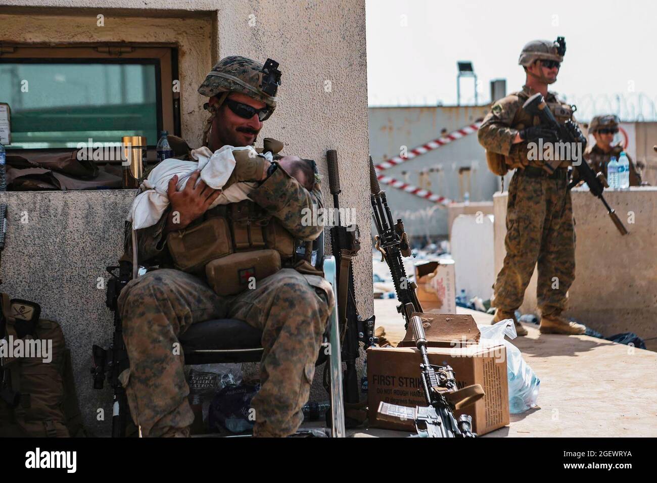 Eine Marine, die der 24. Marine Expeditionary Unit (MEU) zugewiesen wurde, beruhigt ein Kleinkind während einer Evakuierung am Hamid Karzai International Airport, Kabul, Afghanistan, 20. August 2021. US-Dienstmitglieder und Koalitionspartner unterstützen das US-Außenministerium bei einer nicht-kämpferischen Evakuierungsoperation (NEO) in Afghanistan. Pflichtnachweis: Isaiah Campbell/US Marine Corps via CNP /MediaPunch Stockfoto