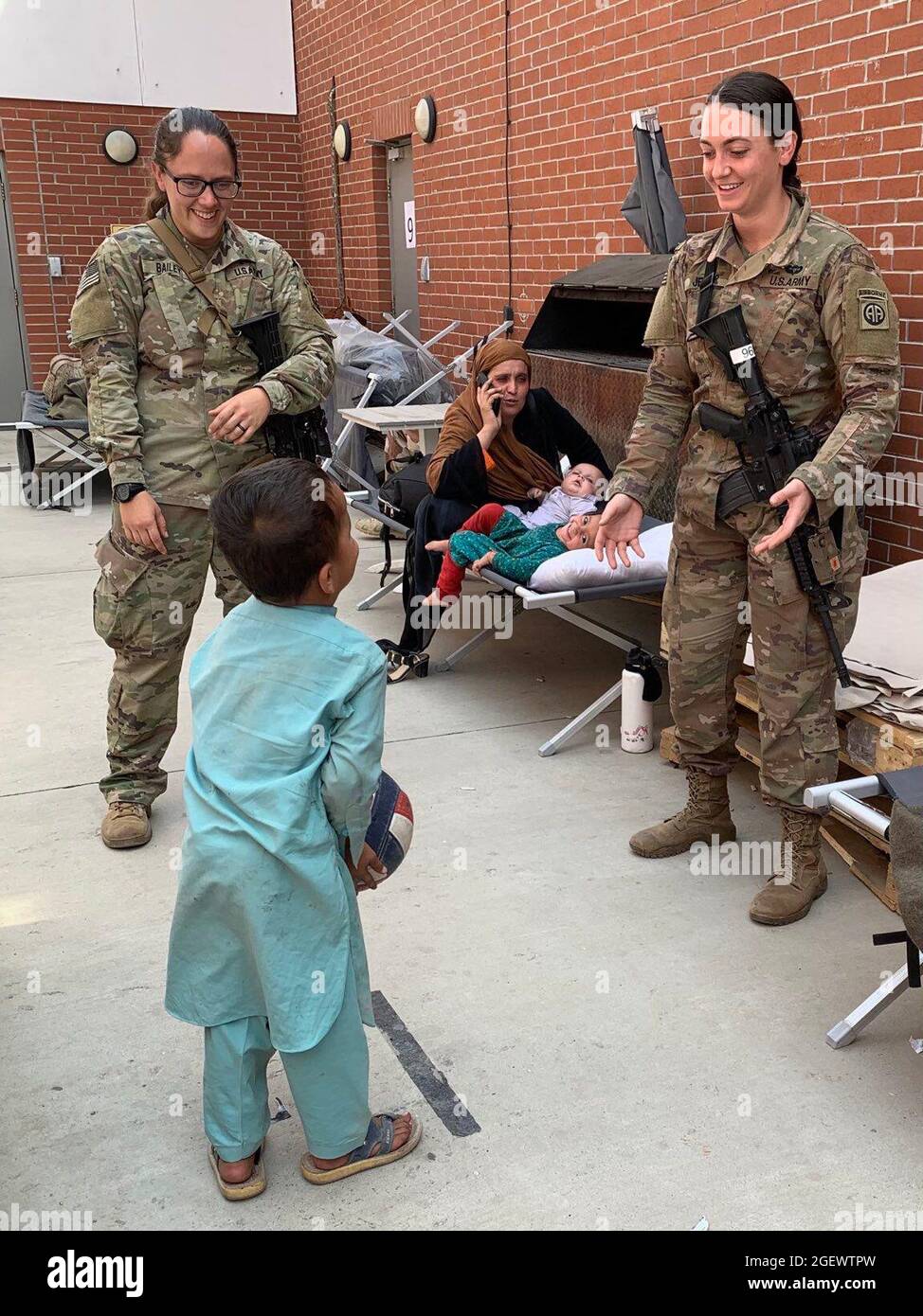 KABUL, AFGHANISTAN - die Spezialistin Julie Bailey und Sergeant Breanna Jessop mit der 82. Airborne Division des XVIII Airborne Corps spielen am Hamid Karzai International Airport im August 20 den Catch mit einem afghanischen Kind. Stockfoto