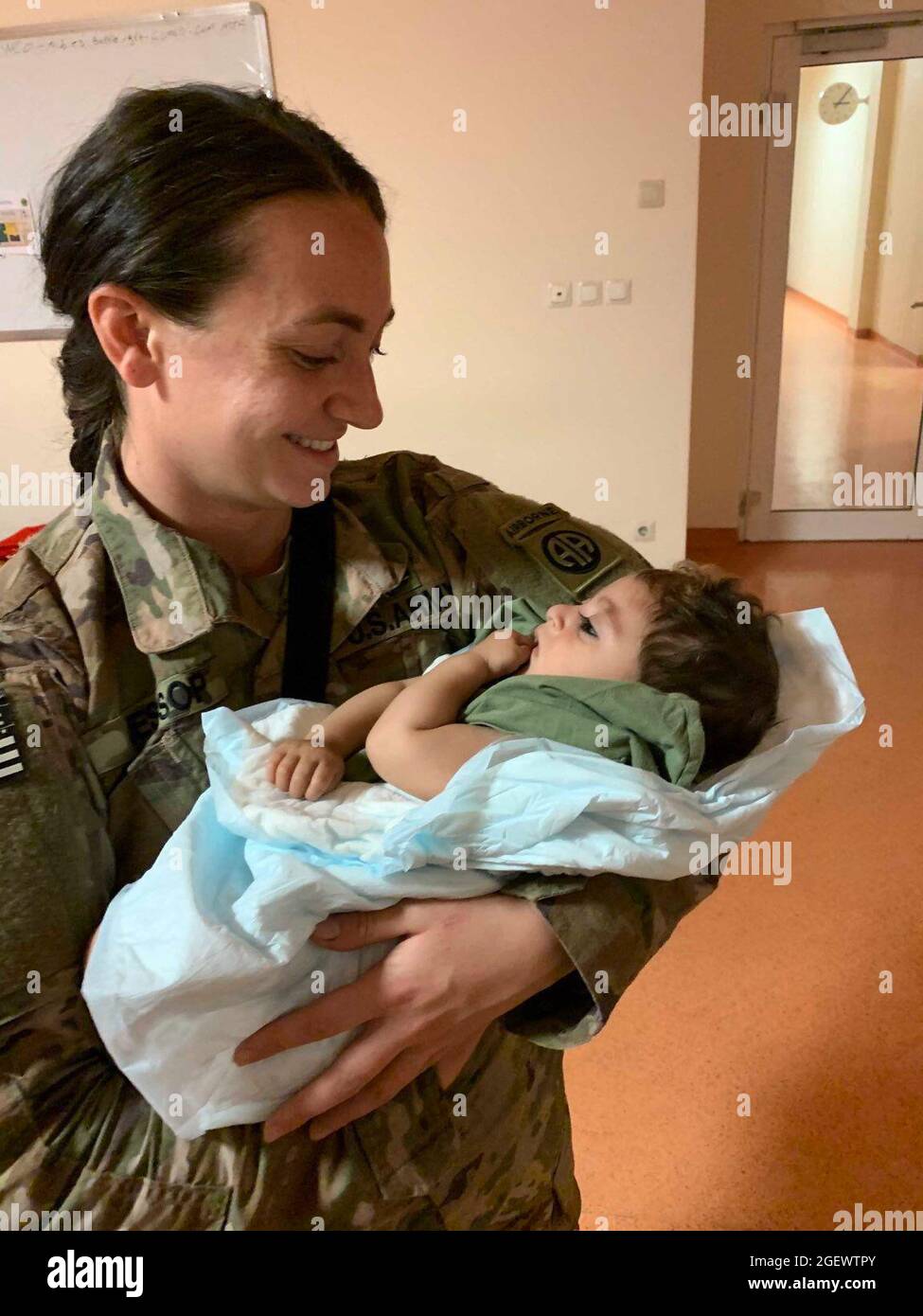 Sergeant Breanna Jessop, eine Führungspersönlichkeit der 82. Airborne Division des XVIII Airborne Corps, kümmert sich im August 20 um ein afghanisches Kind auf dem Hamid Karzai International Airport. Stockfoto