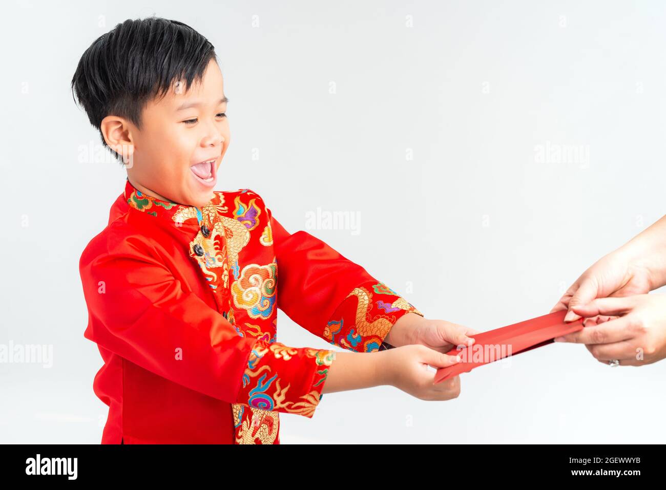 Asiatischer vietnamesischer Junge, der auf dem Mond-Neujahrsfest rote Papiertüten oder Geld von einem anderen erhält, wobei das traditionelle Ao dai auf weißem Hintergrund isoliert ist Stockfoto
