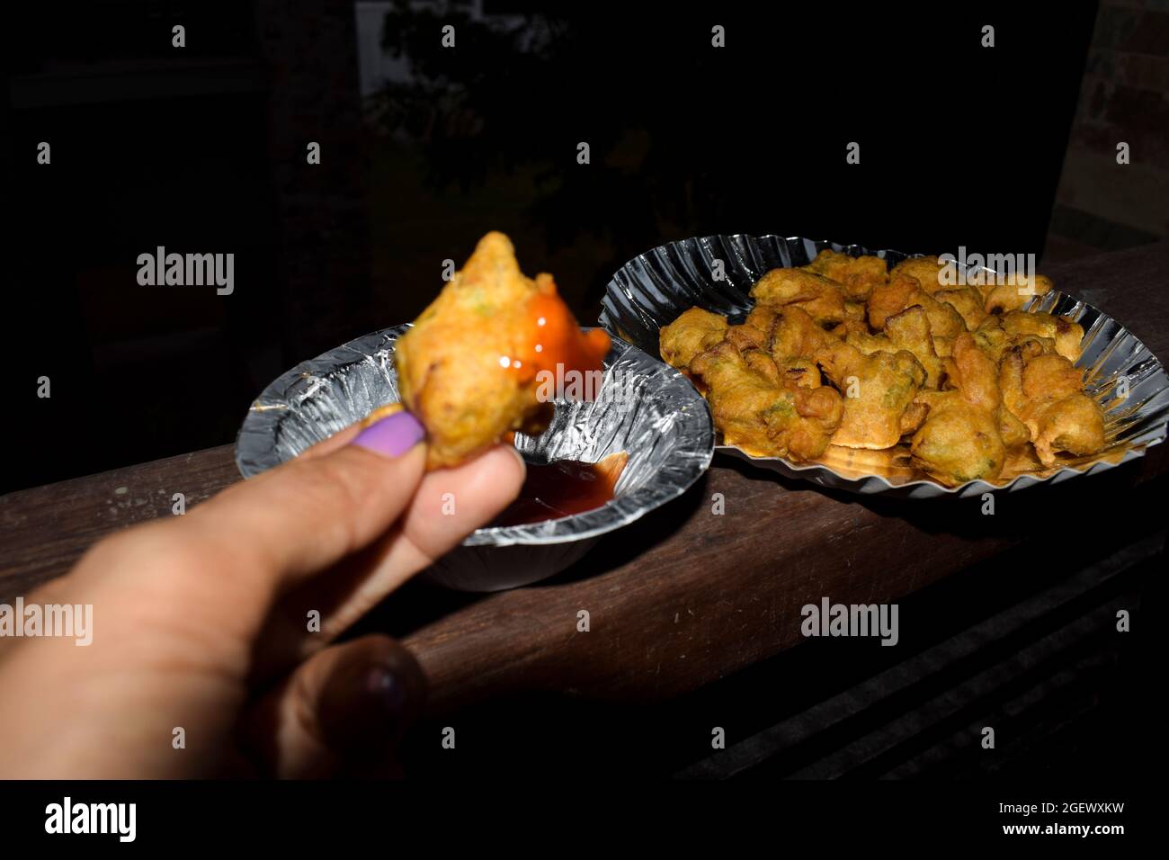 Selektiver Fokus von Zwiebel bhajiya oder Zwiebel fritters . Frau, die Snacks isst Stockfoto