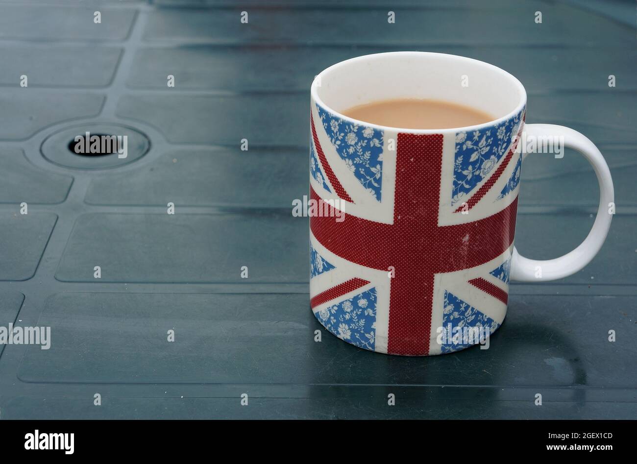 Teetasse mit Union Jack-Thema auf einem grünen Tisch draußen Stockfoto