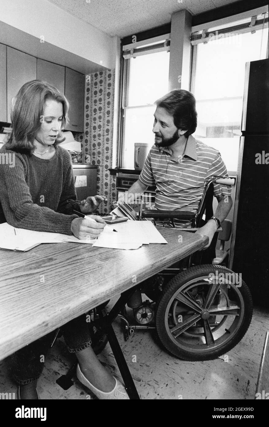 Austin Texas USA, um 1992: Behinderter Mann im Rollstuhl und Ehefrau arbeiten vom Küchentisch aus mit Haushaltsbudget. ©Bob Daemmrich Stockfoto