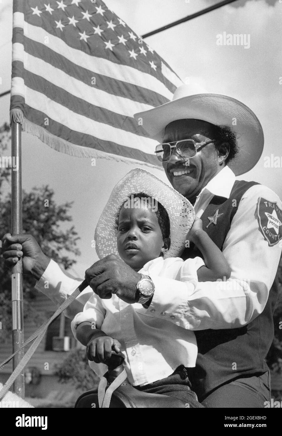 Austin Texas USA, um Juni 1993: Schwarzer Großvater mit amerikanischer Flagge und Enkel reiten während der Junienth-Parade zusammen zu Pferd. ©Bob Daemmrich Stockfoto