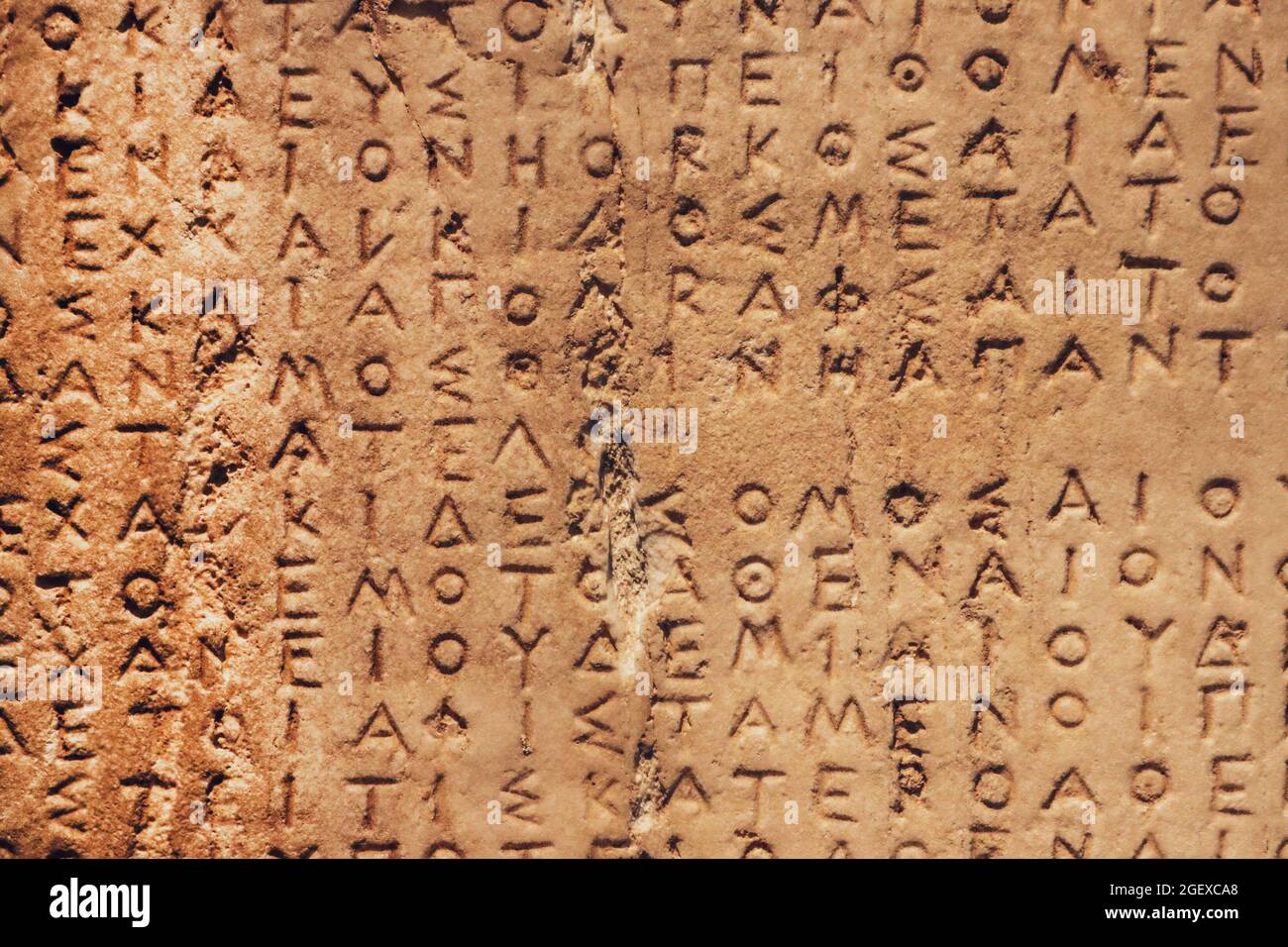 Fragment der alten abgenutzten griechischen Buchstaben auf grobem körnigen Stein geschnitzt - Archäologie. Stockfoto