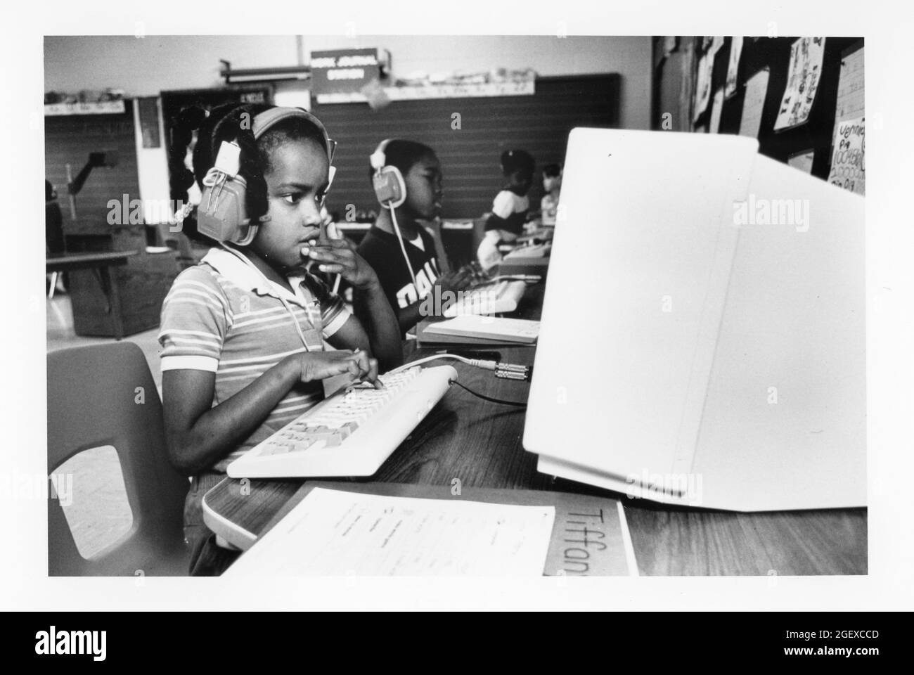 Austin Texas USA, um 1990: Schüler der ersten Klasse verwenden Kopfhörer, um computergestützte Lehrprogramme zum Schreiben von Geschichten zu hören. ©Bob Daemmrich Stockfoto