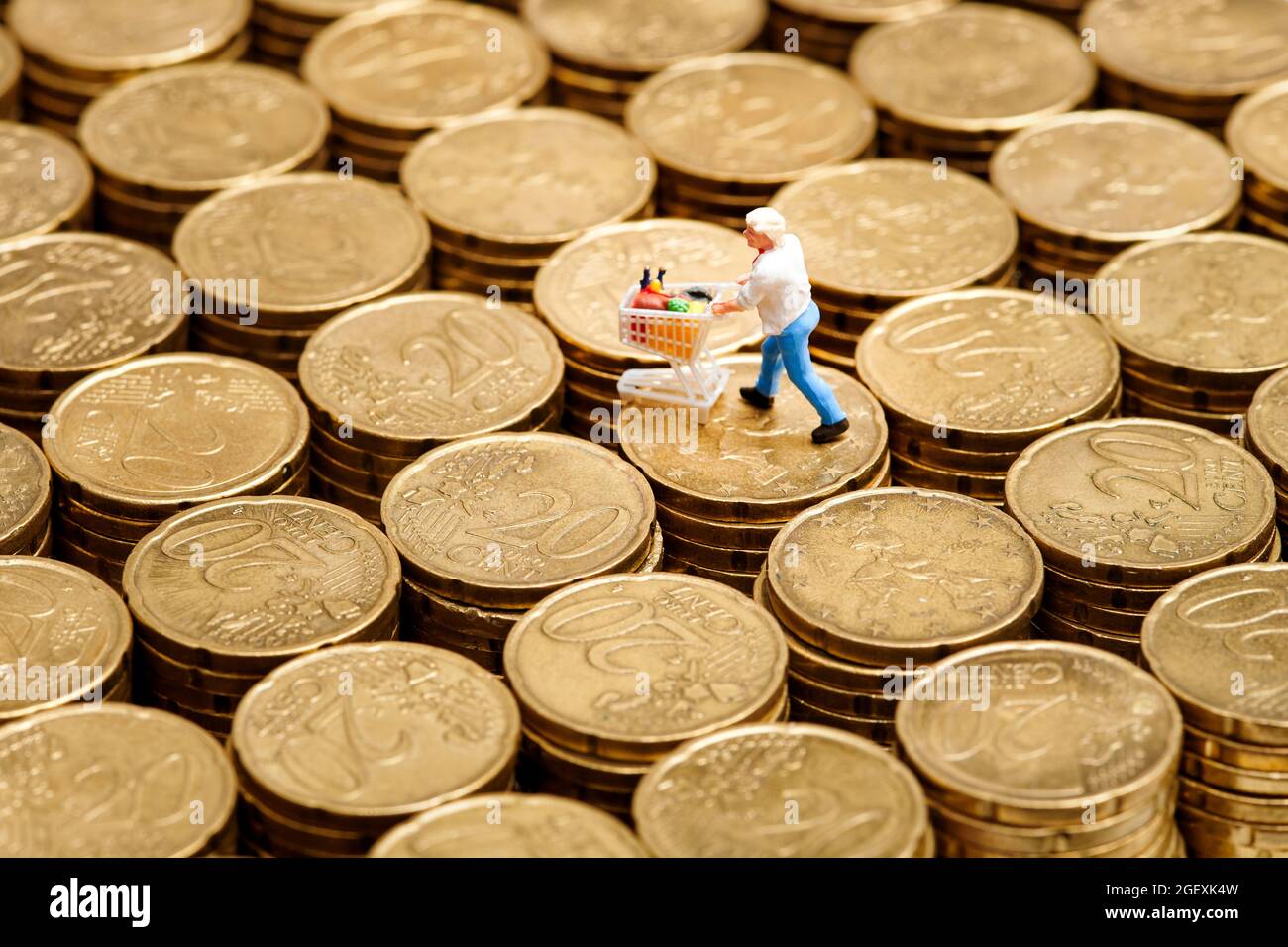 Nahaufnahme Miniatur-Mann mit Einkaufswagen auf Stapeln mit 20-Cent-Euro-Münzen platziert Stockfoto