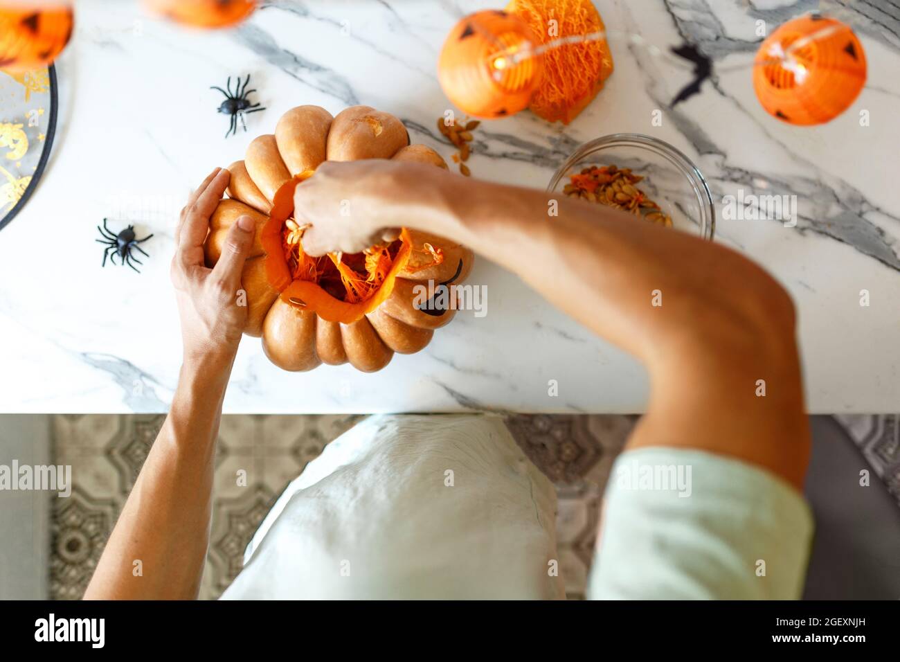 Eine Nahaufnahme von Menschenhand zieht Samen und faseriges Material von einem Kürbis, bevor er zu Halloween schnitzen kann. jack-o-Laterne. Draufsicht Stockfoto