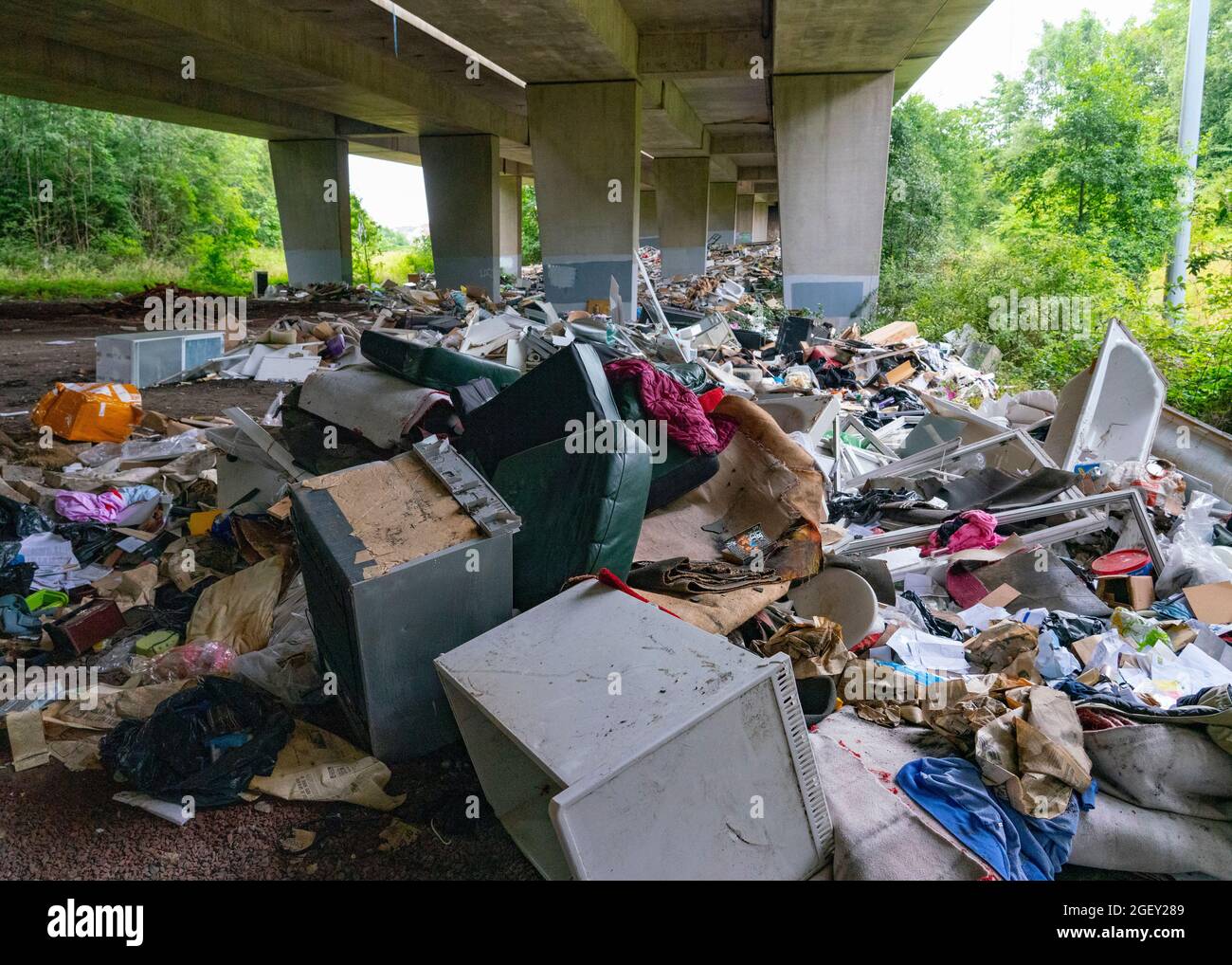 Eine riesige Menge illegaler Abfälle von Baustellen und Haushalten, die unter dem Viadukt M8, Glasgow, Schottland, gedumpt wurden Stockfoto